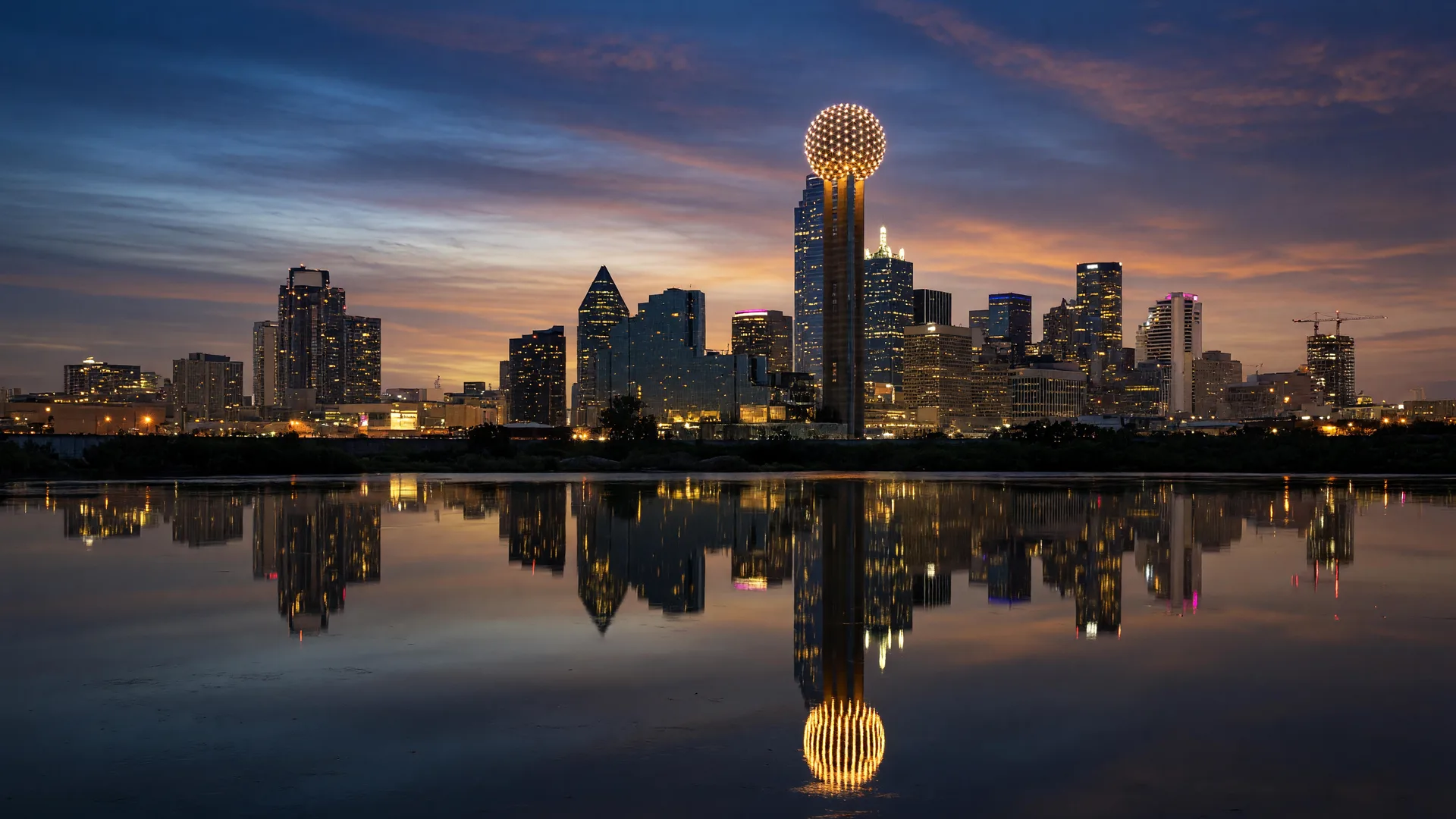 The Dallas skyline at dusk with Reunion Tower glowing against a deep blue and amber sky