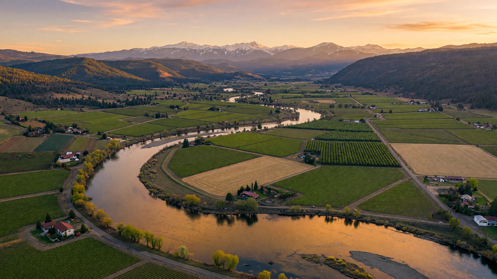 Aerial view of the Rogue River winding through the Rogue Valley with vineyards and mountains