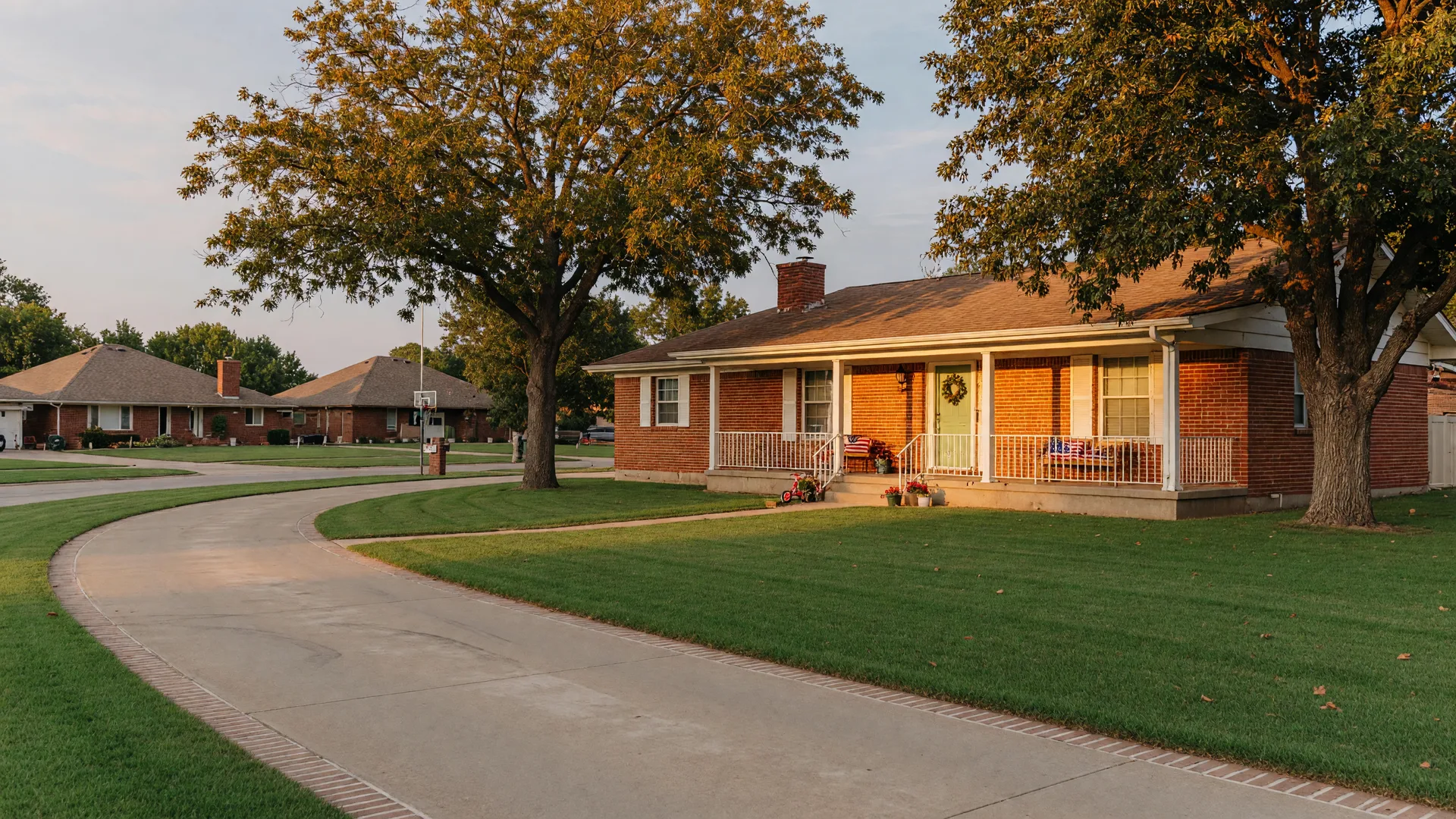 Brick ranch home in a Tulsa Metro suburb with a covered porch and a curved concrete driveway in late afternoon light