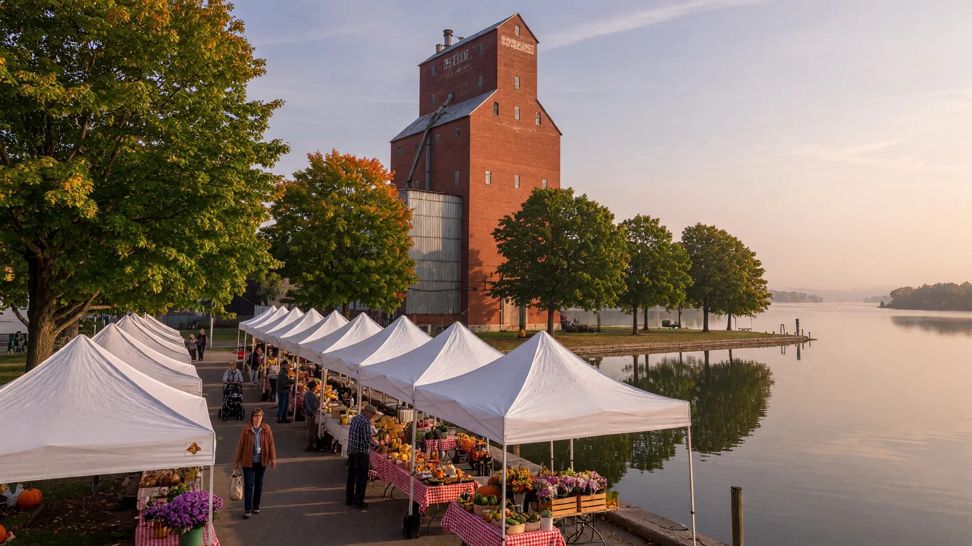 White farmers' market tents along the Port Perry lakefront at the foot of Queen Street on a late September morning, with the historic grain elevator rising beside Lake Scugog