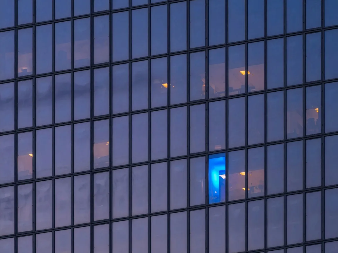 Glass skyscraper facade at dusk with one electric blue window pane
