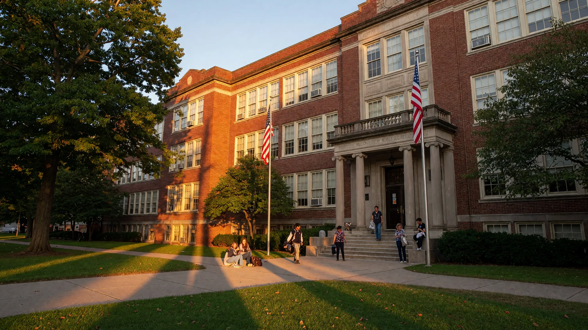 Historic brick public school building in Bloomfield NJ on a late summer afternoon with American flags and well-maintained grounds