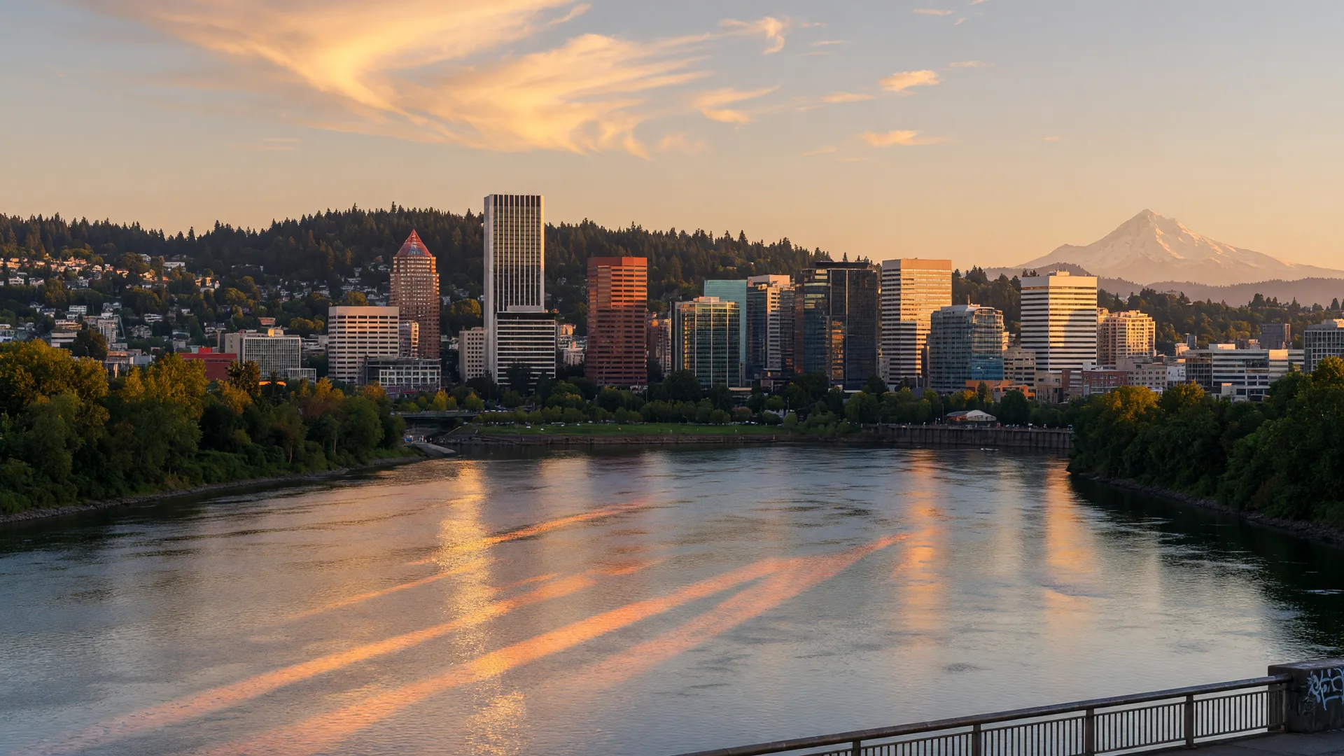Portland Oregon skyline at golden hour in mid-September seen across the Willamette River with forested southwest hills behind downtown