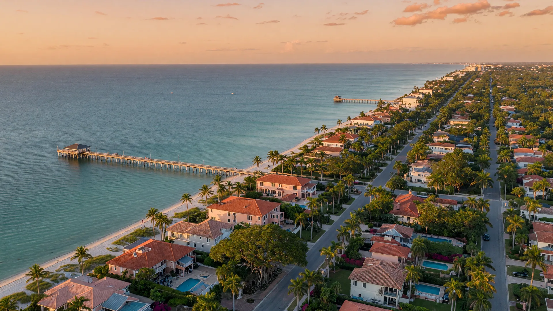Aerial view of downtown Naples, Florida at golden hour with the Old Naples street grid, the Naples Pier, and the Gulf of Mexico