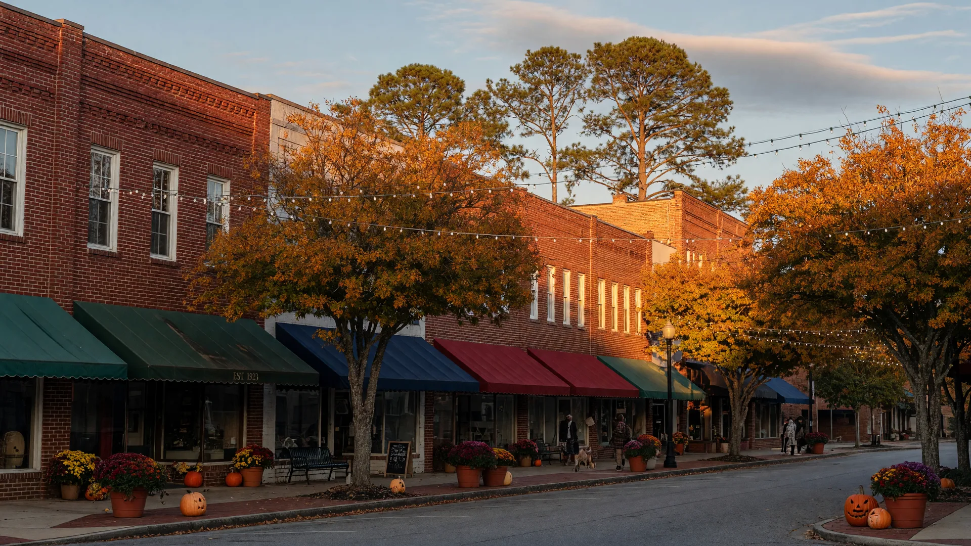 Downtown Southern Pines brick storefronts with fall foliage and pumpkins on a golden October afternoon
