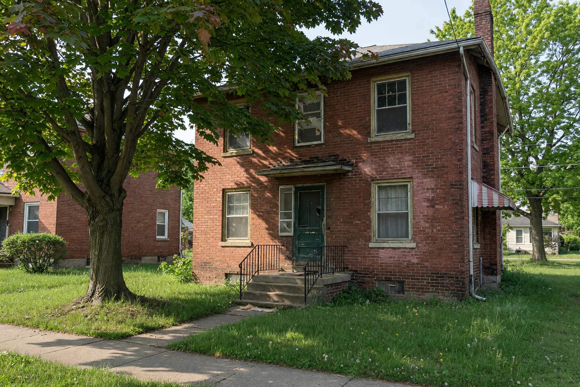 A slightly worn older brick house in Northeast Ohio with mature trees and character