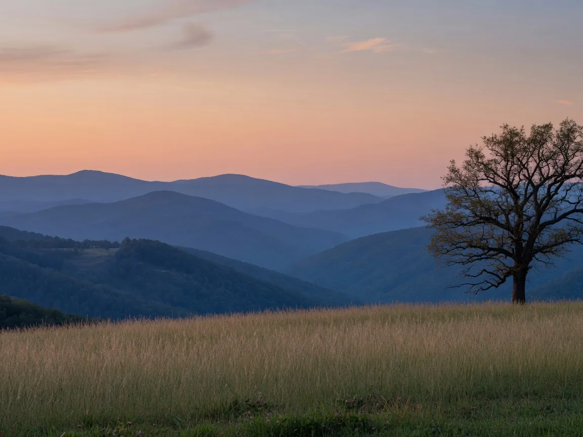 Layered blue North Georgia mountain ridges seen from a pasture meadow at dusk