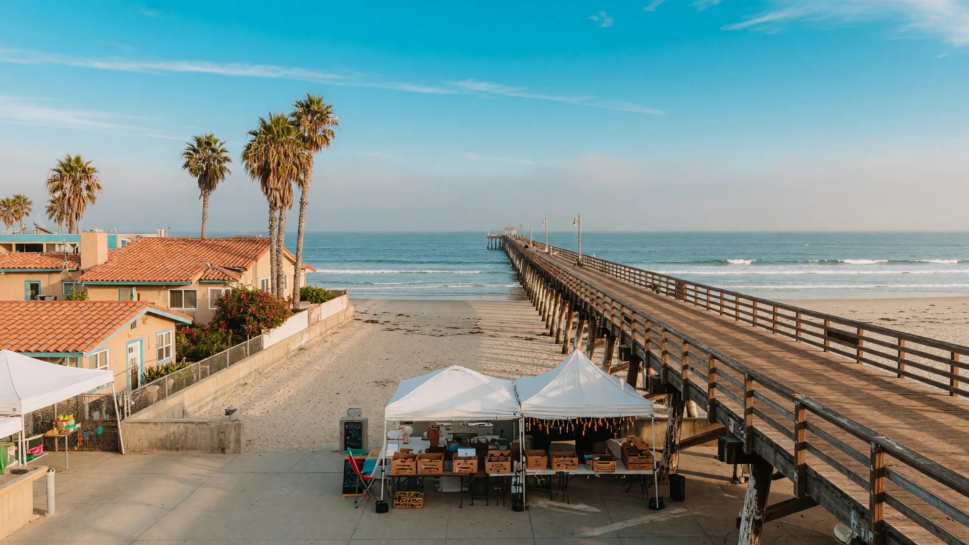 The Imperial Beach Pier on a bright late-September morning with market tents at the pier entrance and palm-lined beach homes along Seacoast Drive in ZIP 91932