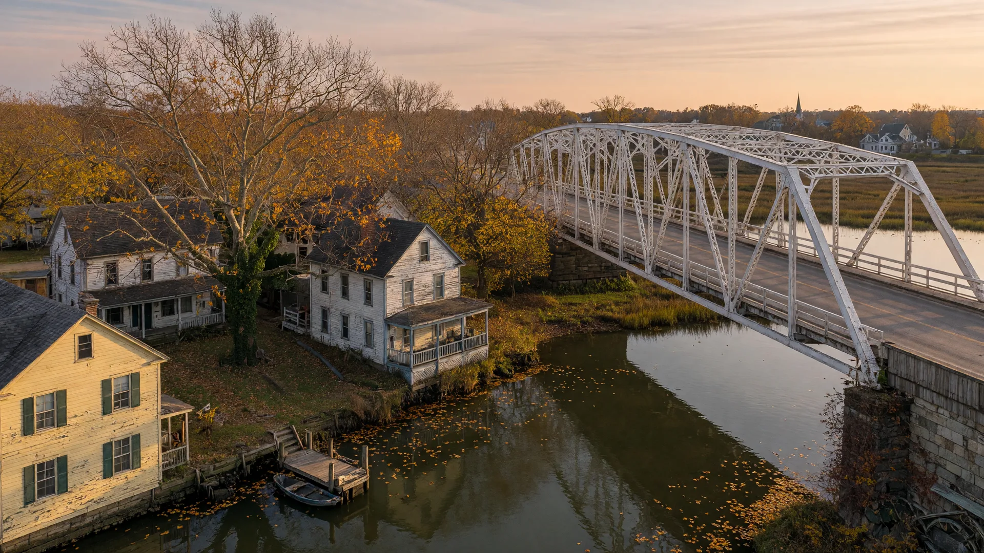 A white bridge crossing the Rancocas Creek with historic clapboard houses along the bank in autumn light