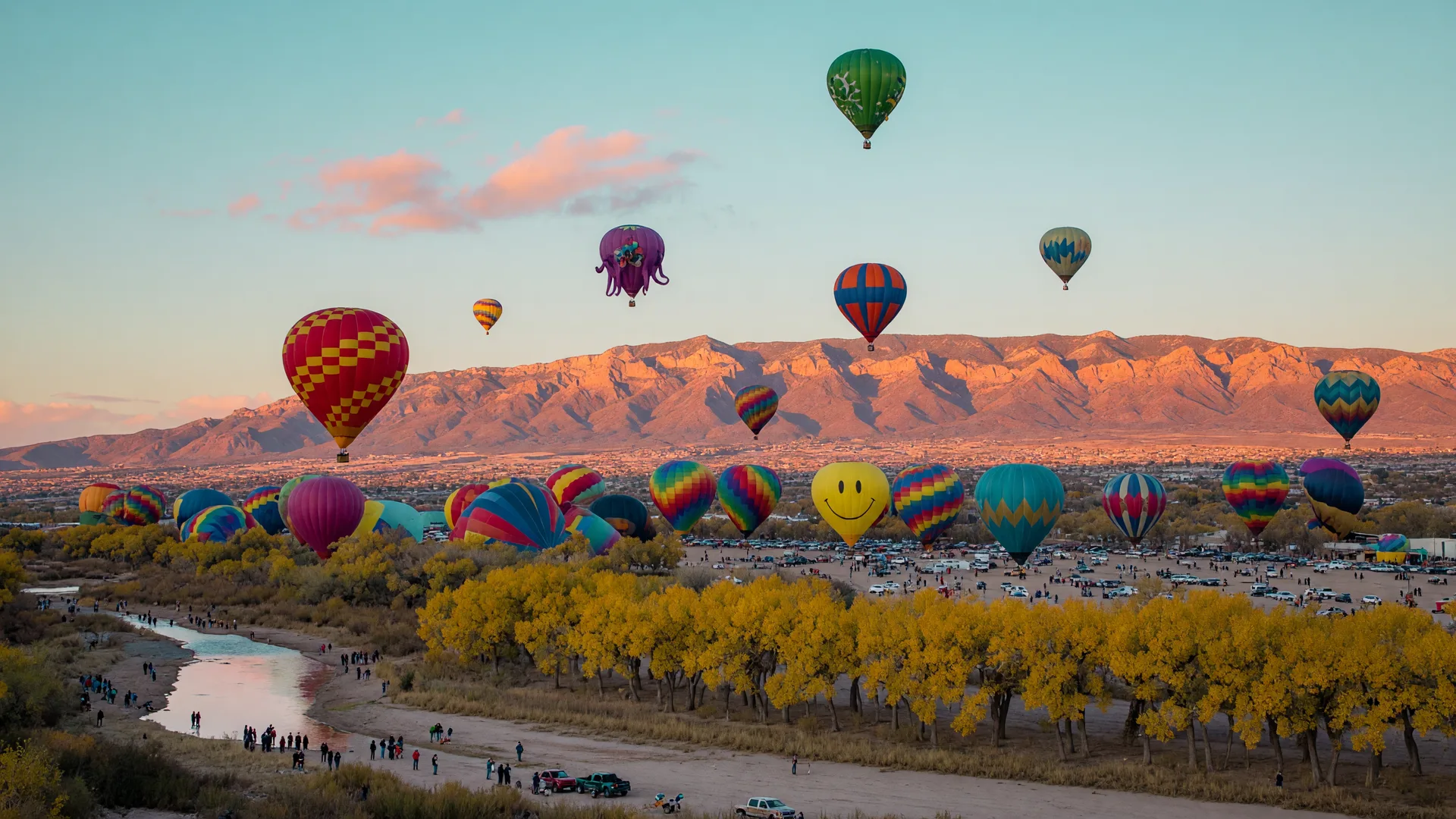 Hot air balloons rising over the Rio Grande valley at dawn with the Sandia Mountains glowing in the background