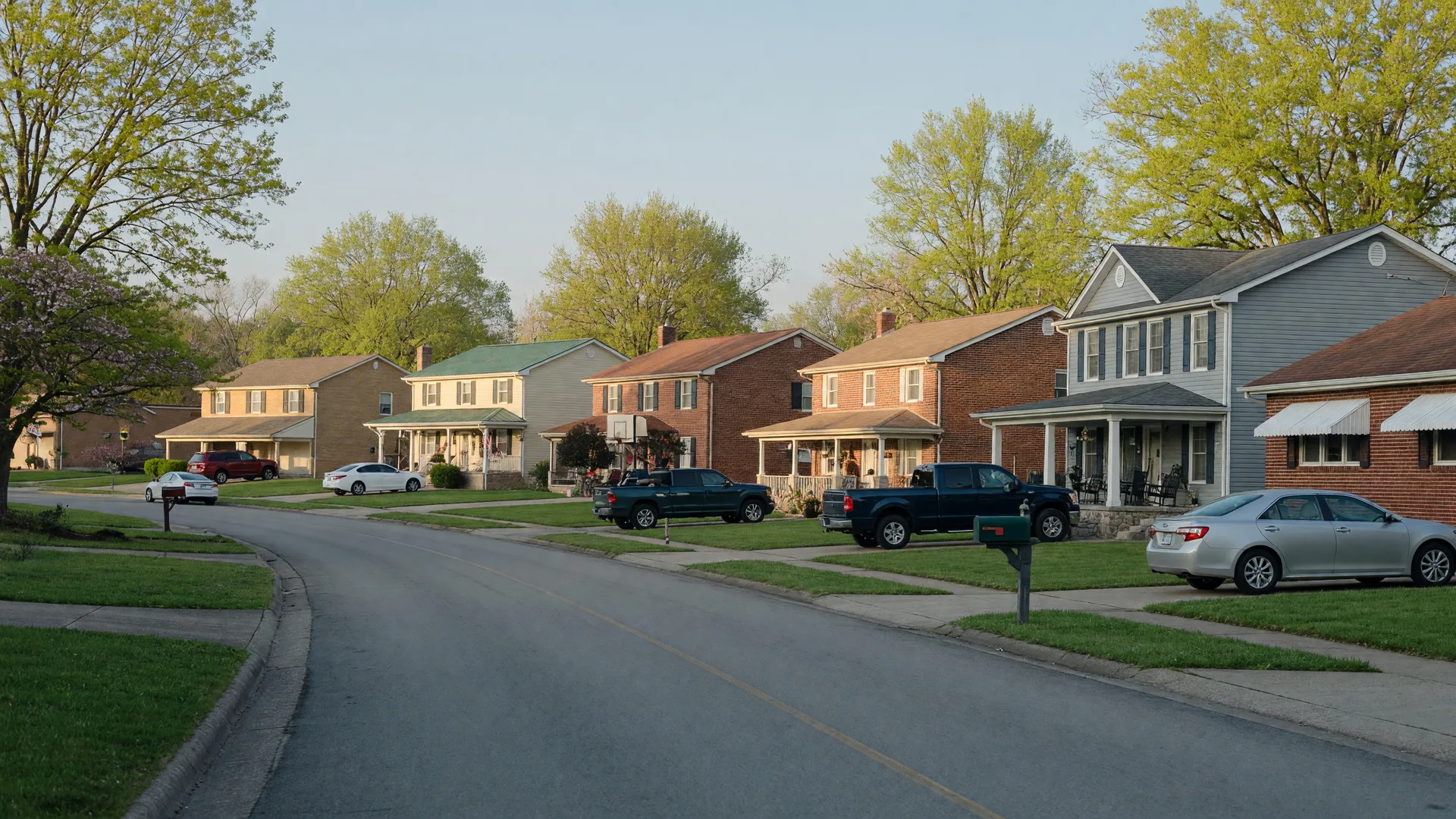 A quiet street of mixed brick and craftsman homes in a small Kentucky town on a clear spring morning