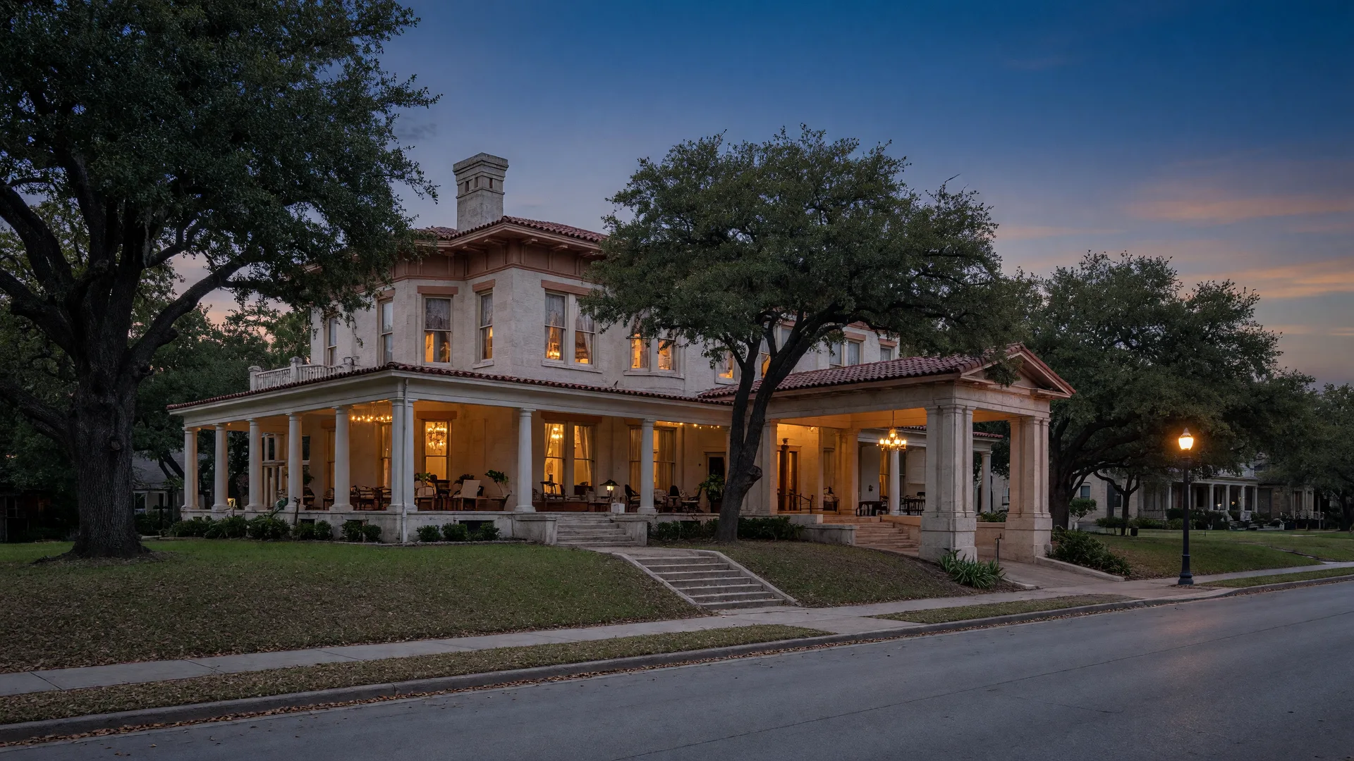 Grand 1910s mansion with porte-cochere on a Monte Vista boulevard, a stately San Antonio real estate address, at dusk