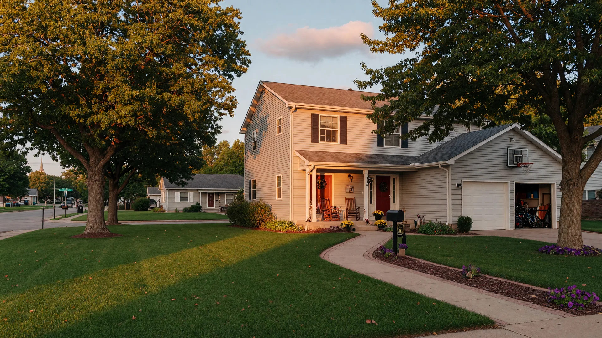 A well-kept two-story family home with a two-car garage in a leafy Sioux Falls neighborhood at golden hour