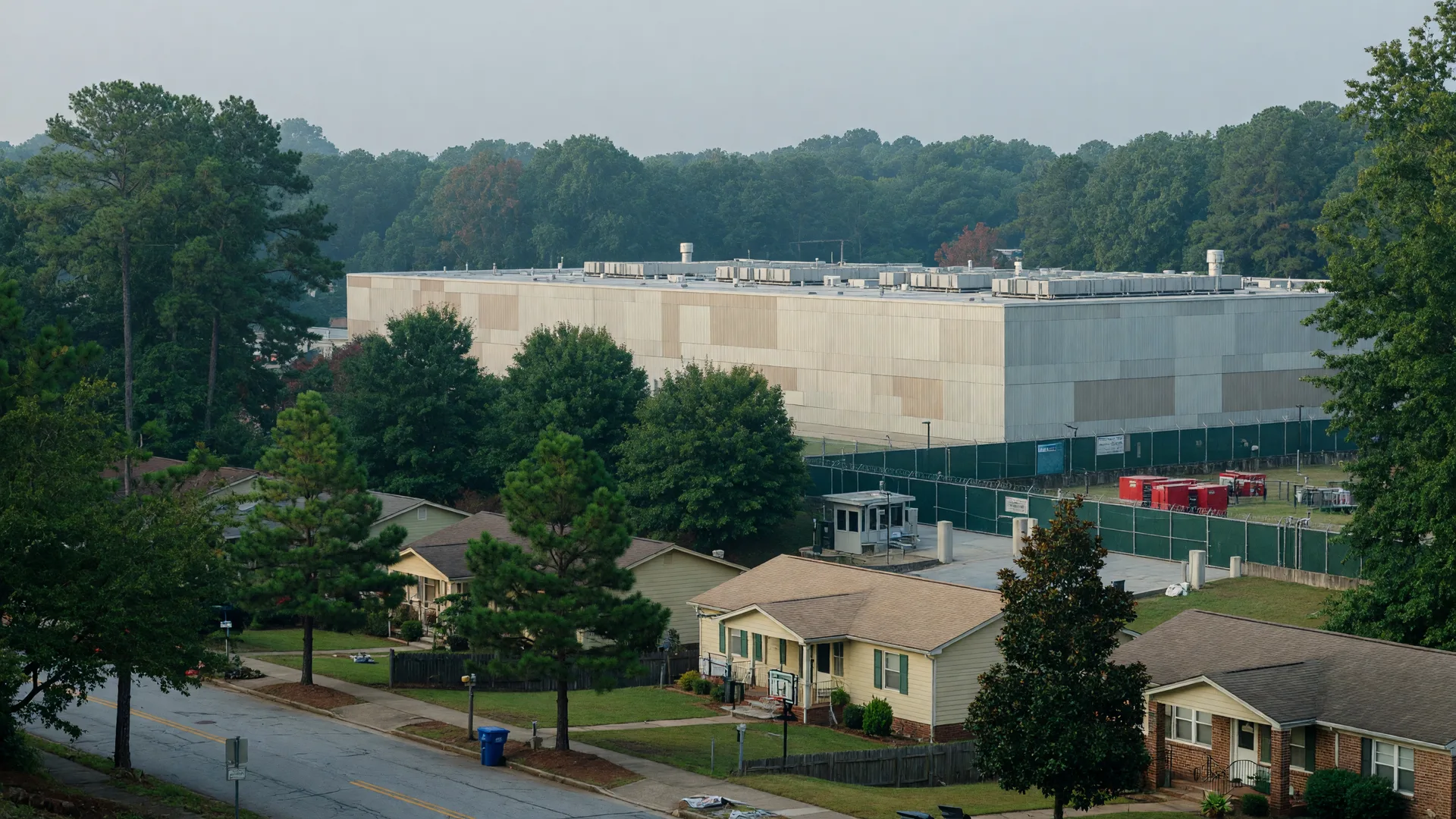 A large data center facility set back behind a tree buffer on the edge of a quiet suburban neighborhood in Metro Atlanta