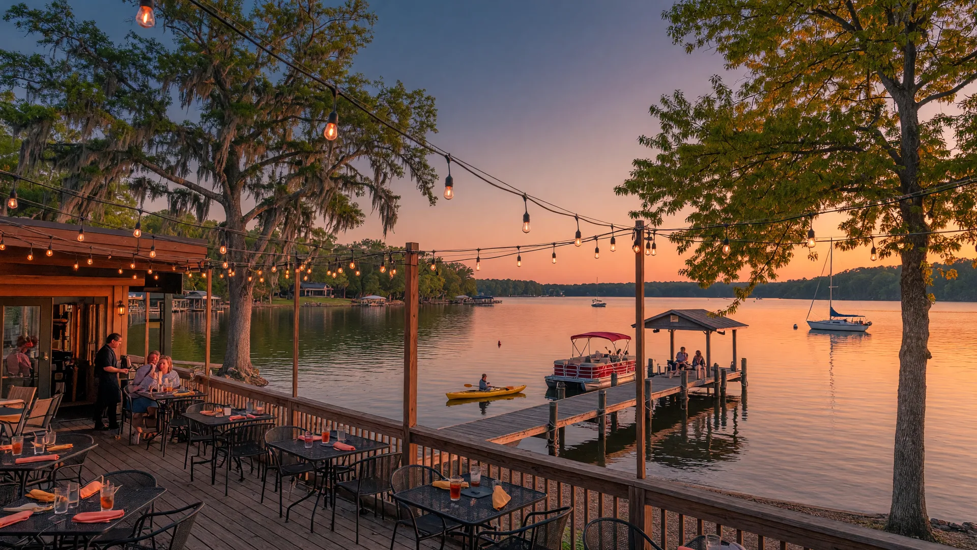 Lake Acworth at golden hour with a lakeside restaurant patio, string lights, boats on the water, and a pier extending into the calm lake