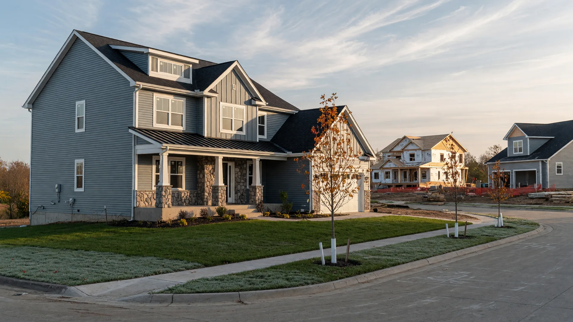A newly constructed craftsman-style home with gray siding and a stone-accented porch in a Clark County Ohio subdivision on a frosty October morning