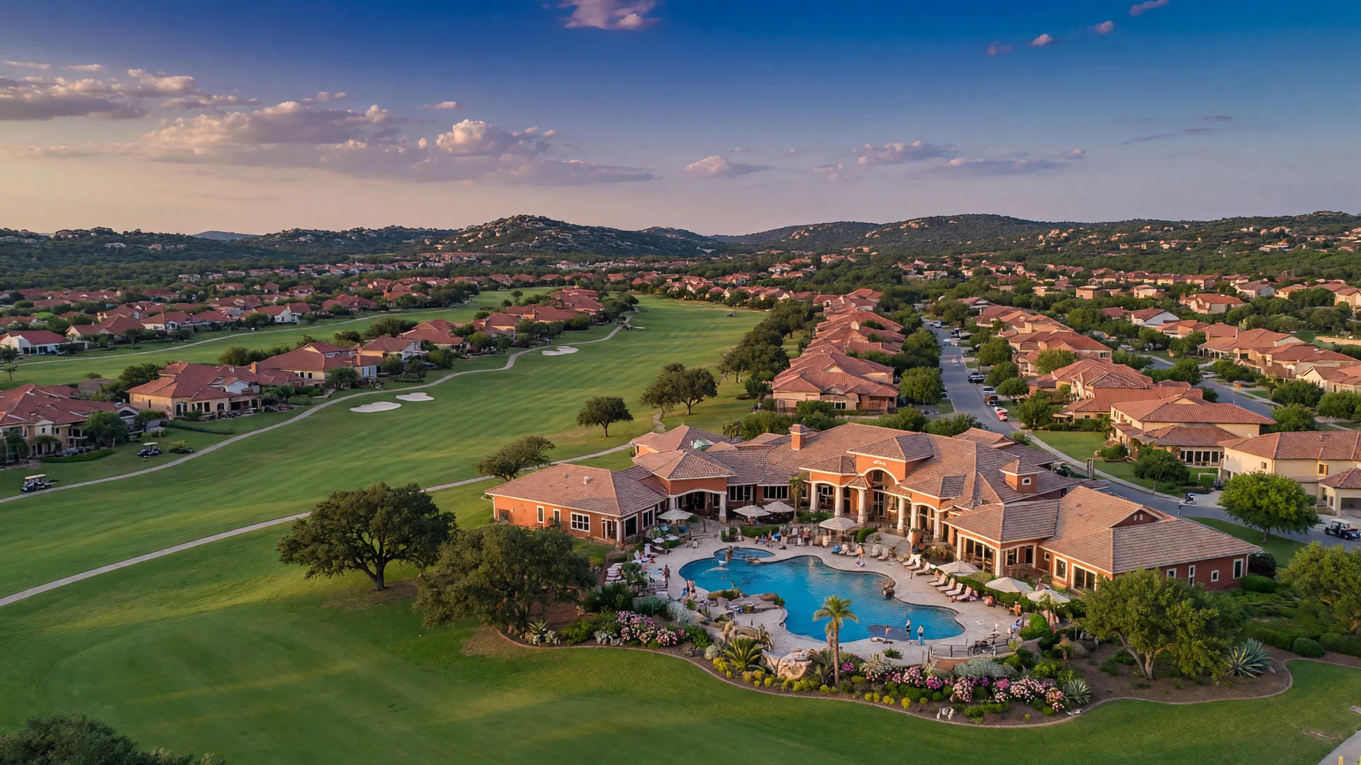 Aerial view of Sun City Georgetown showing resort-style clubhouse, swimming pool, golf fairways, and single-story homes in the Texas Hill Country