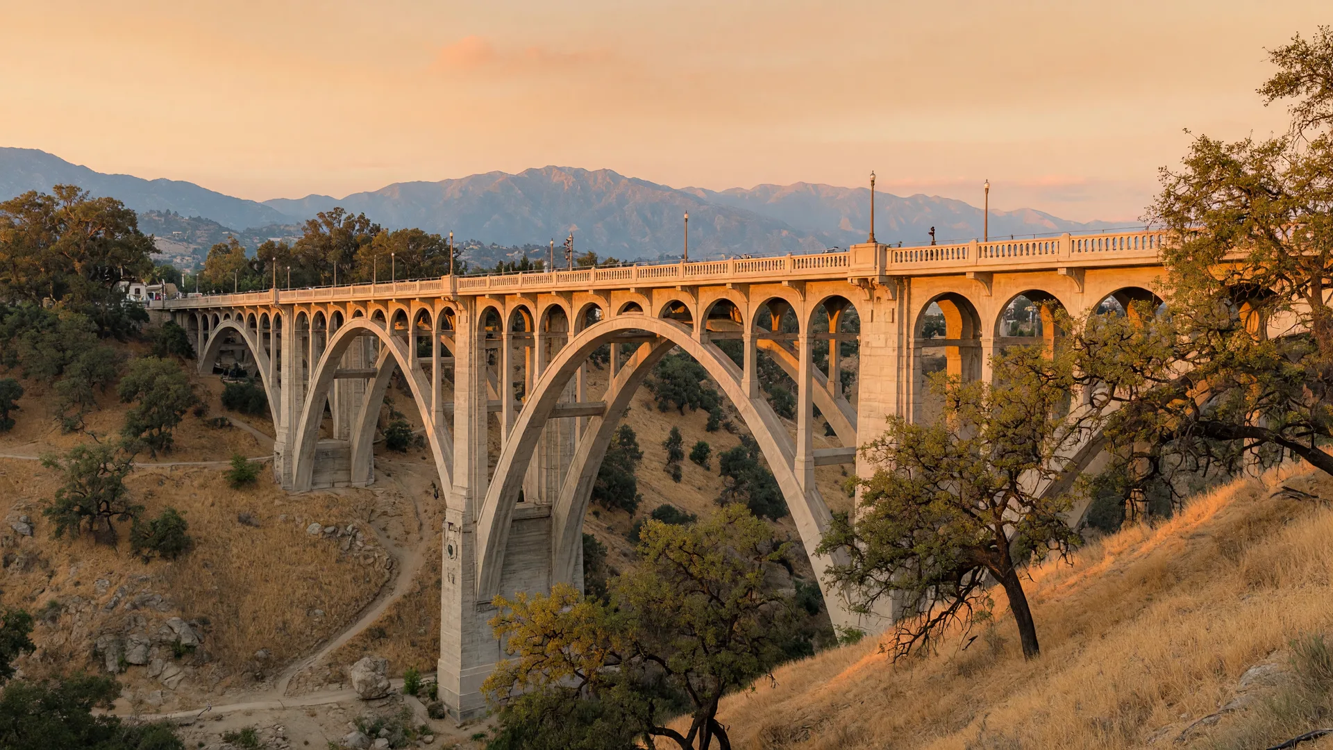 The arched Colorado Street Bridge in Pasadena under warm late-September evening light, with the San Gabriel Mountains beyond