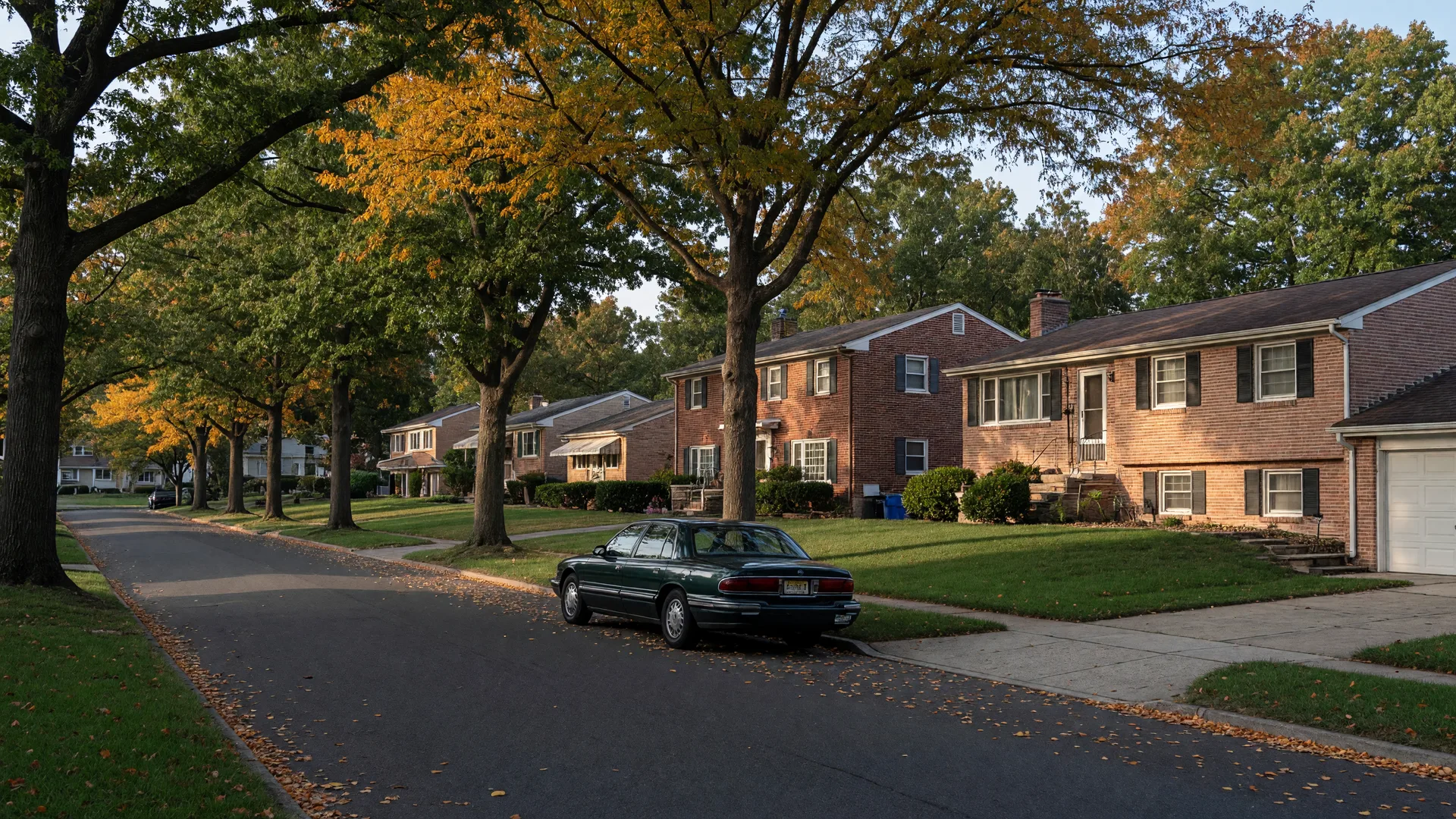 Tree-lined street of mid-century brick ranch and split-level homes in the Kingston Estates section of Cherry Hill, New Jersey on a mid-October afternoon with the first autumn color on the oaks