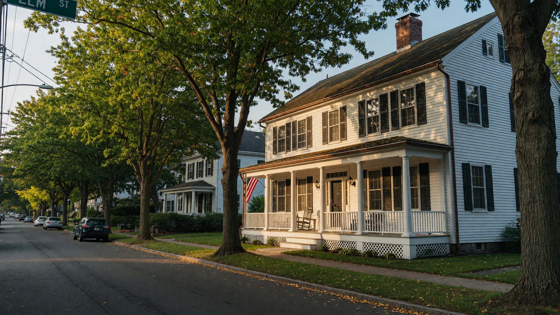 A classic white clapboard colonial family home in Hamden, Connecticut on a quiet tree lined street in early fall light