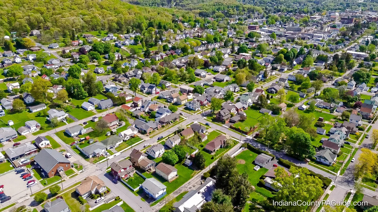 Aerial view of Indiana, PA showing vibrant green trees and a charming residential neighborhood
