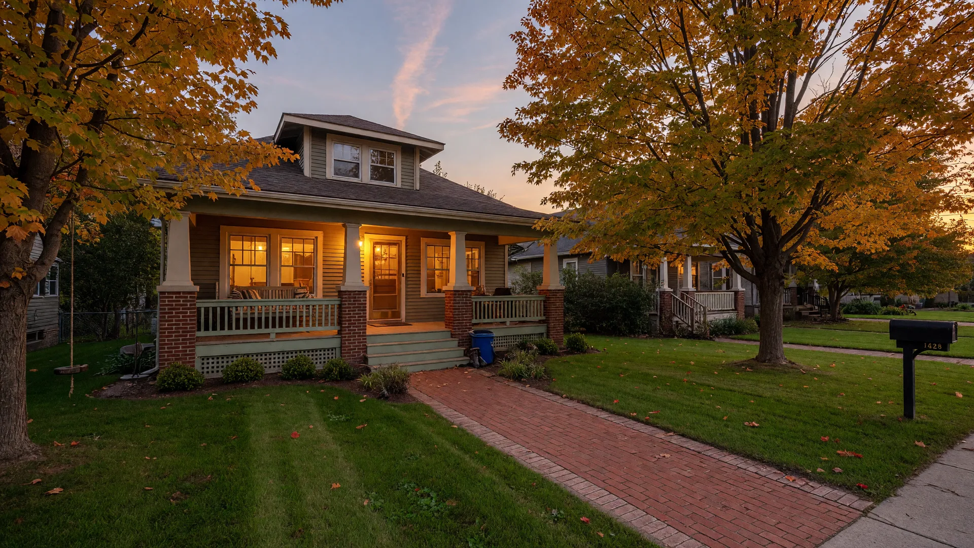A welcoming Mid-Michigan home at golden hour with glowing windows and a brick walkway, seen from the street