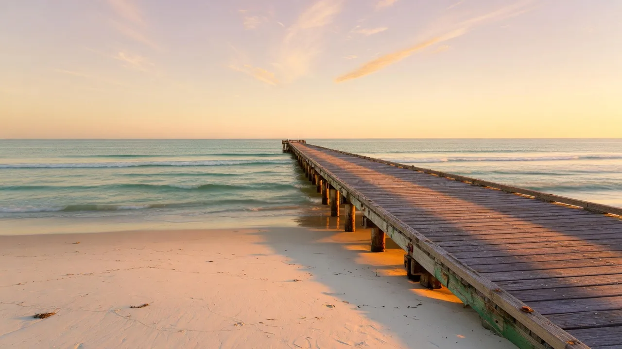 A long wooden pier over Pacific swells in warm evening light