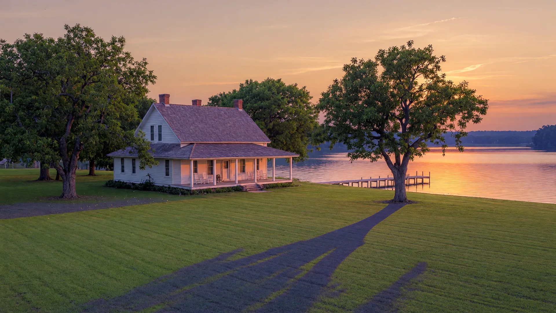 Historic white farmhouse with pecan trees overlooking Lake Hartwell at golden hour