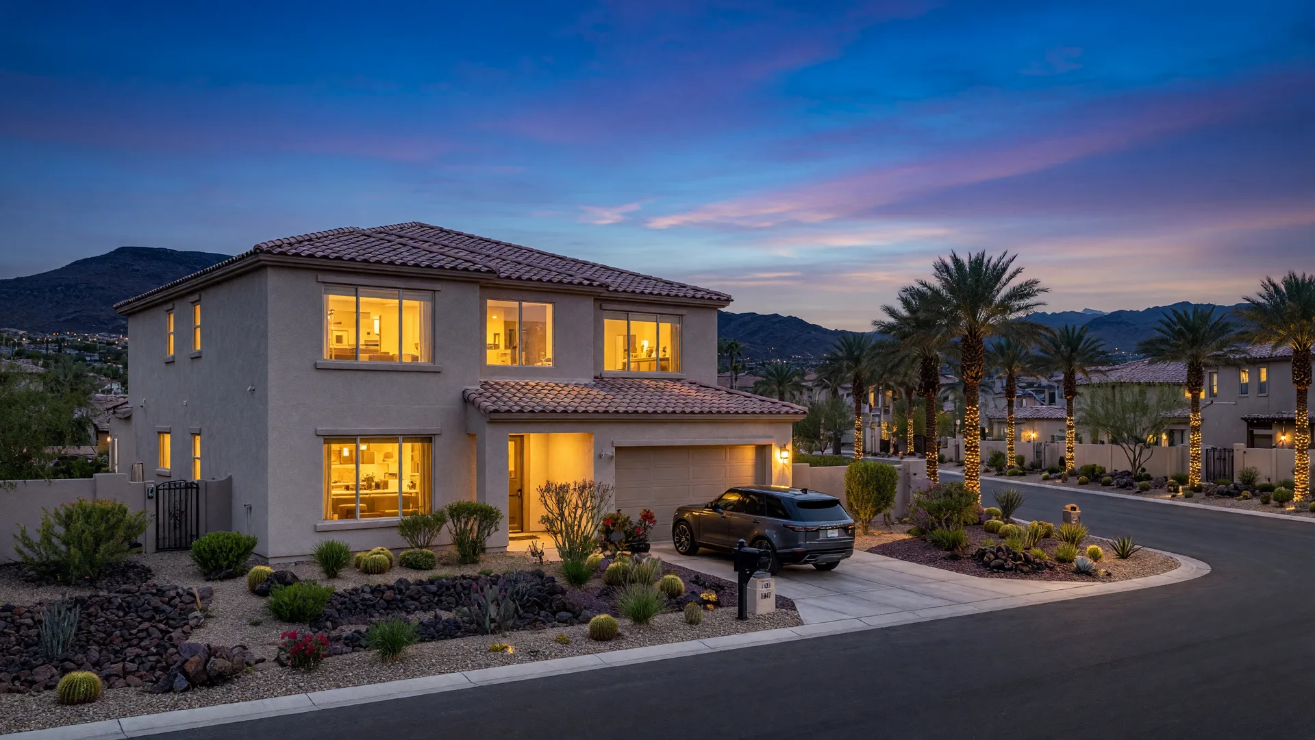 Two-story stucco home with a tile roof and desert landscaping in a gated master-planned Las Vegas neighborhood at dusk