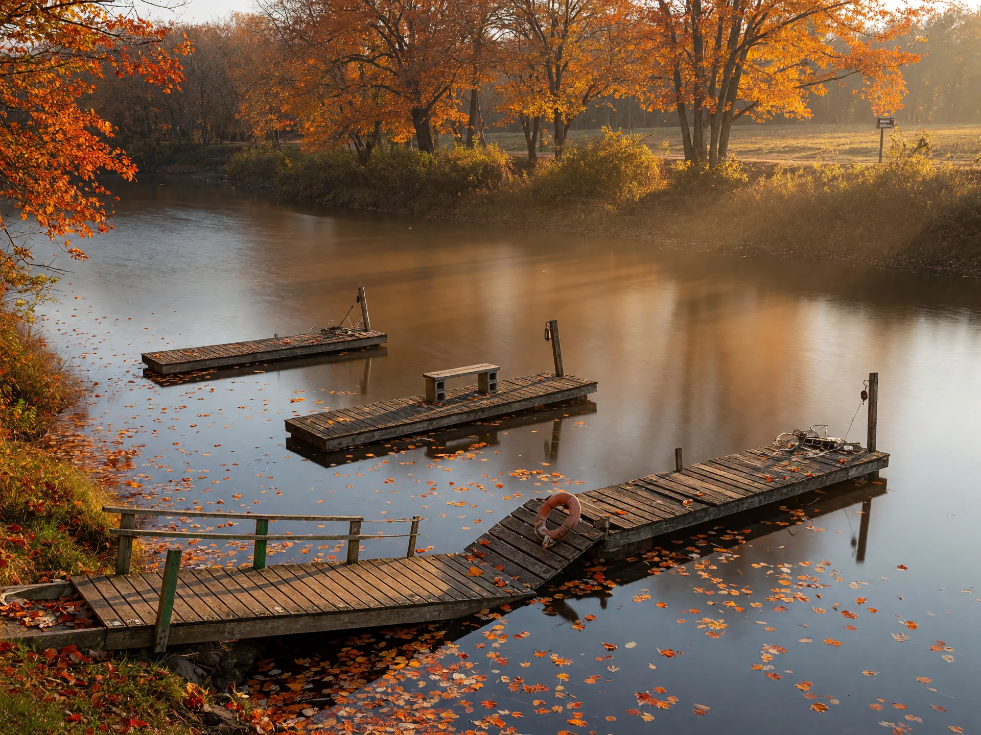 A calm, tree-lined stretch of the Flint River with wooden fishing piers at Flushing Township Nature Park