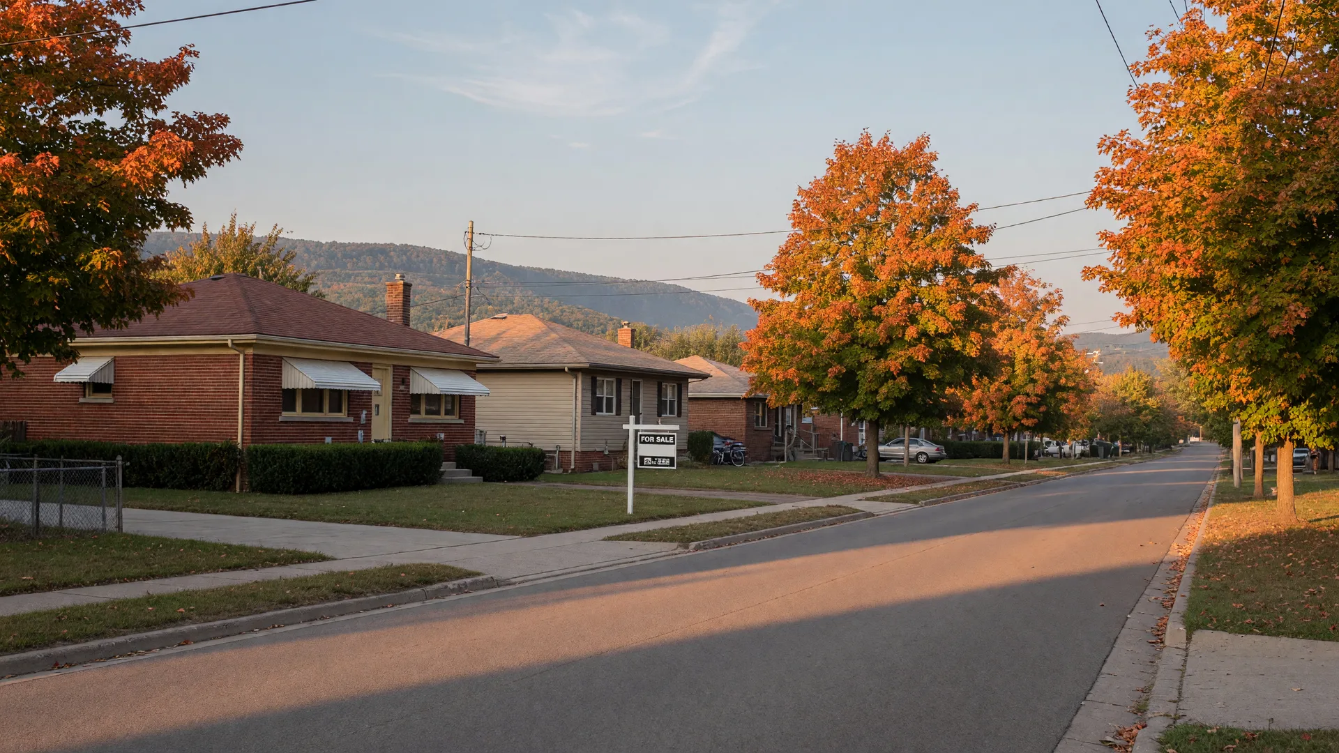 Brick bungalows and a For Sale sign on a quiet Hamilton Mountain street in late September with maples beginning to turn gold