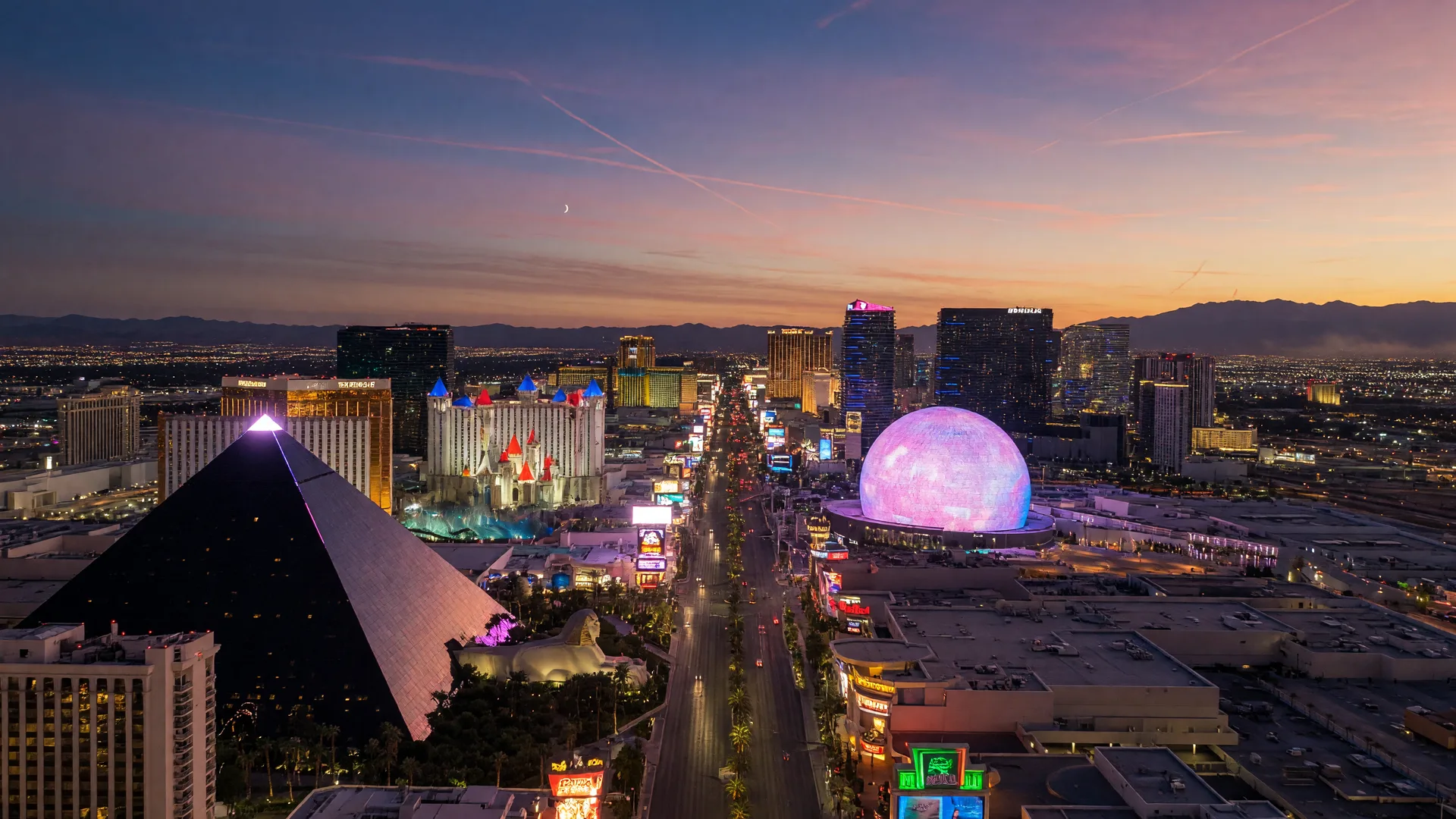 The Las Vegas Strip at dusk with glowing resort towers and mountains on the horizon