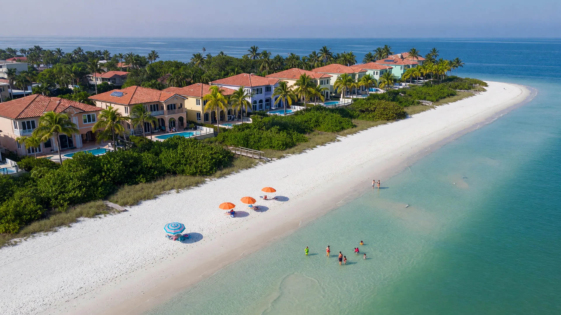 Aerial view of the Gulf of Mexico shoreline in Naples, Florida, with turquoise water, white sand, and beach homes