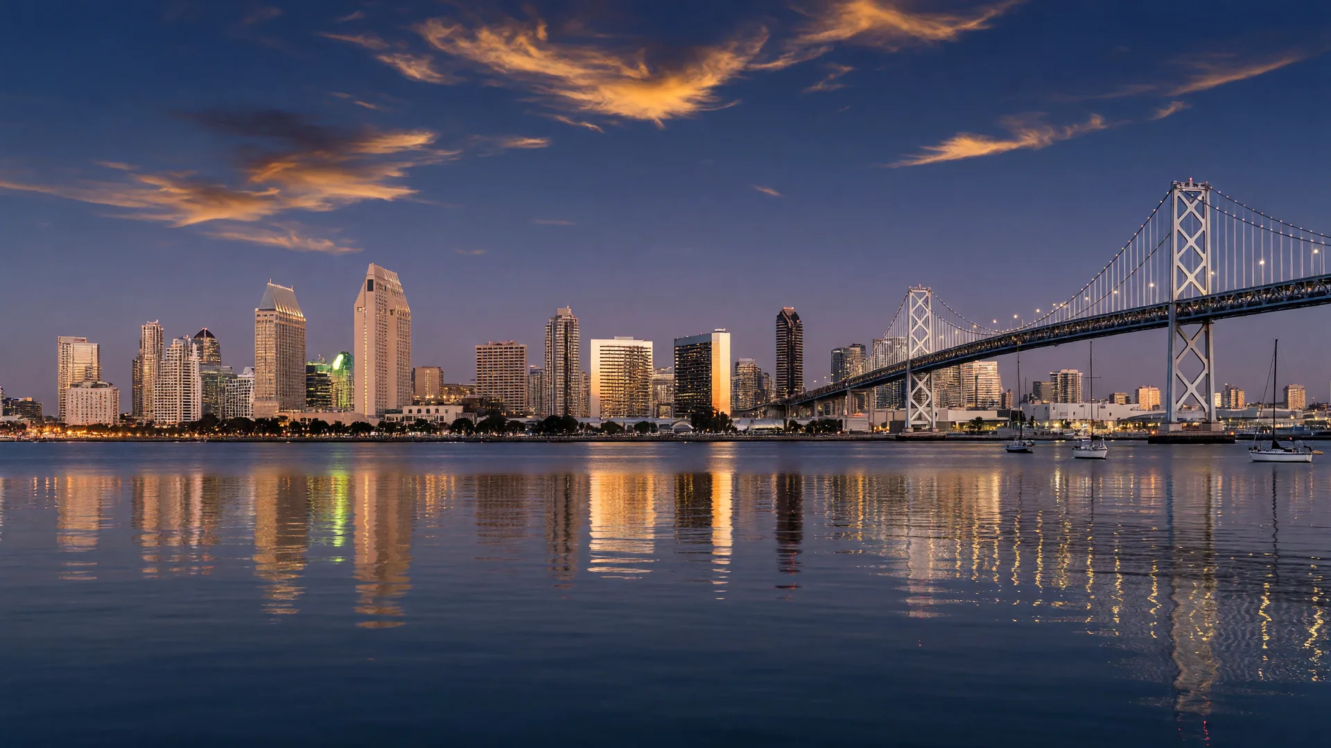 The San Diego skyline and Coronado Bridge at dusk, downtown towers reflecting warm light across the bay