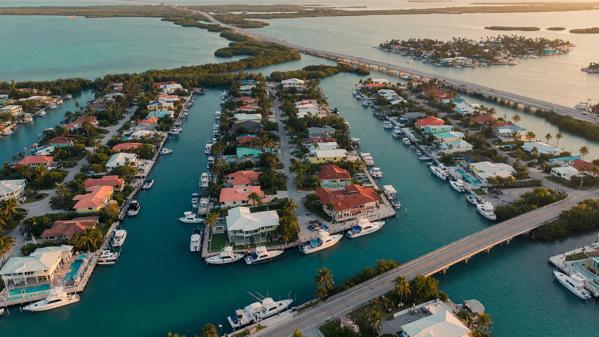 An elevated view of the Upper Florida Keys waterfront communities with deep-water canals lined by luxury homes and private docks at golden hour