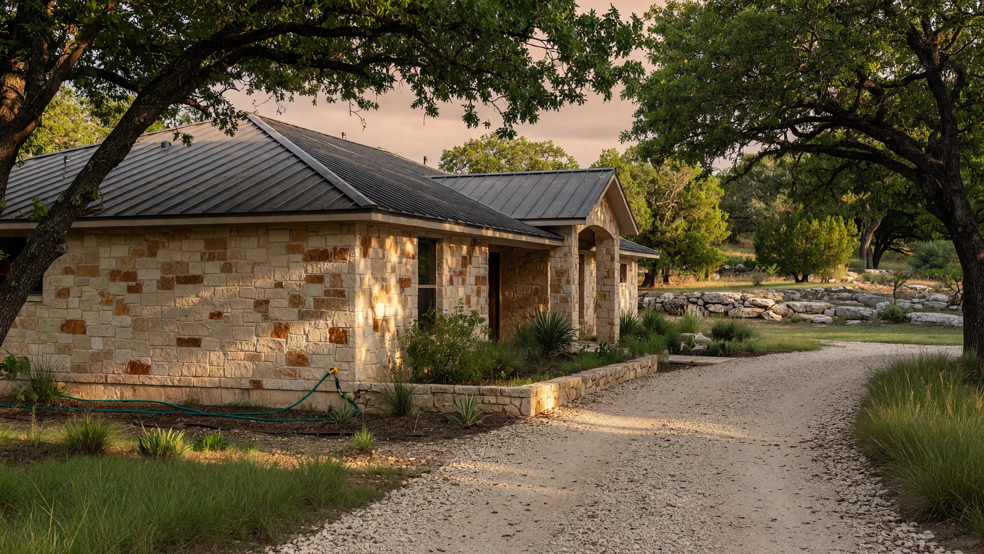 Texas Hill Country home with limestone facade, live oak trees, and native landscaping in warm afternoon light
