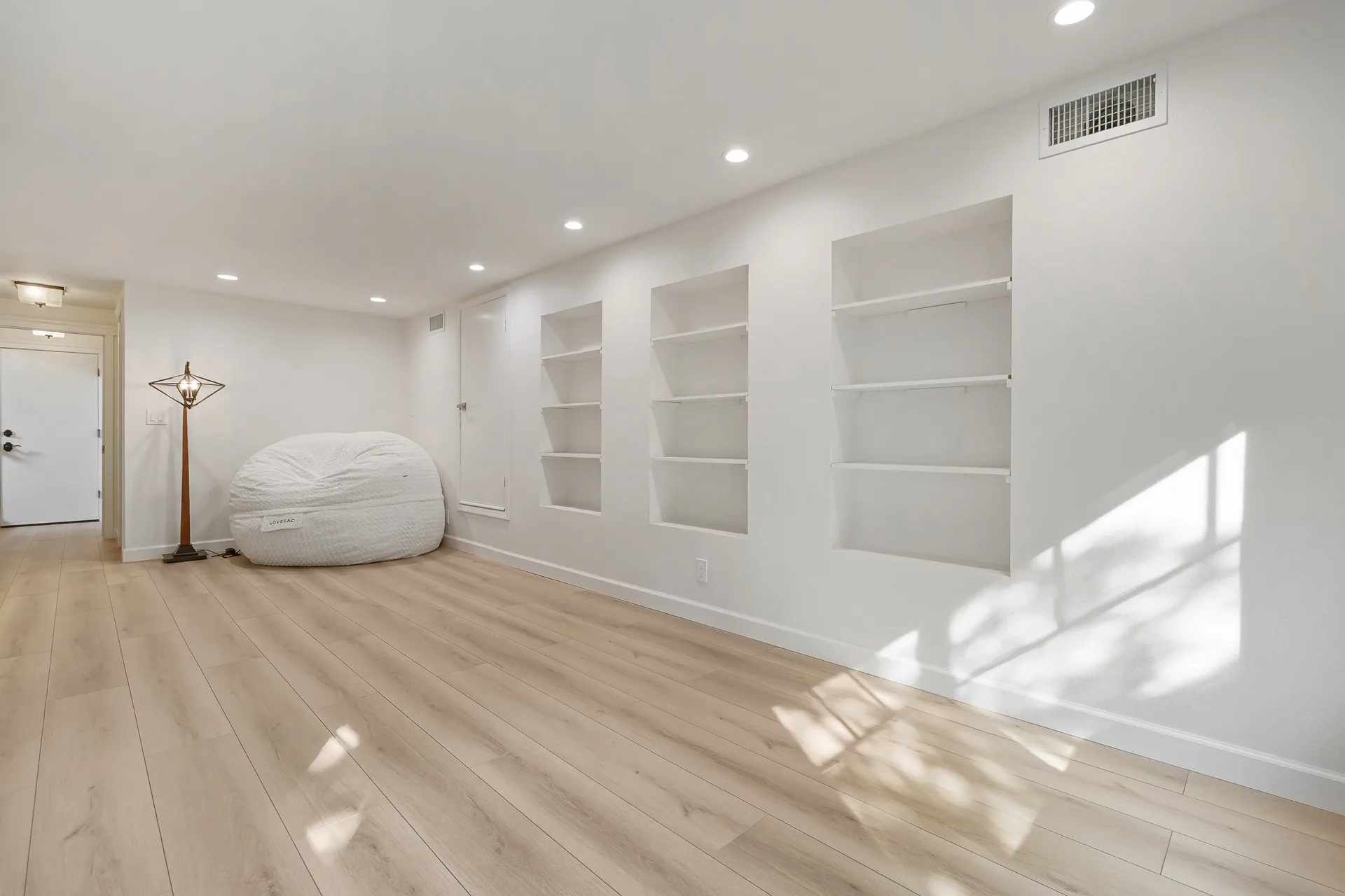 Family room with built-in wall niches, recessed lighting and light hardwood floors