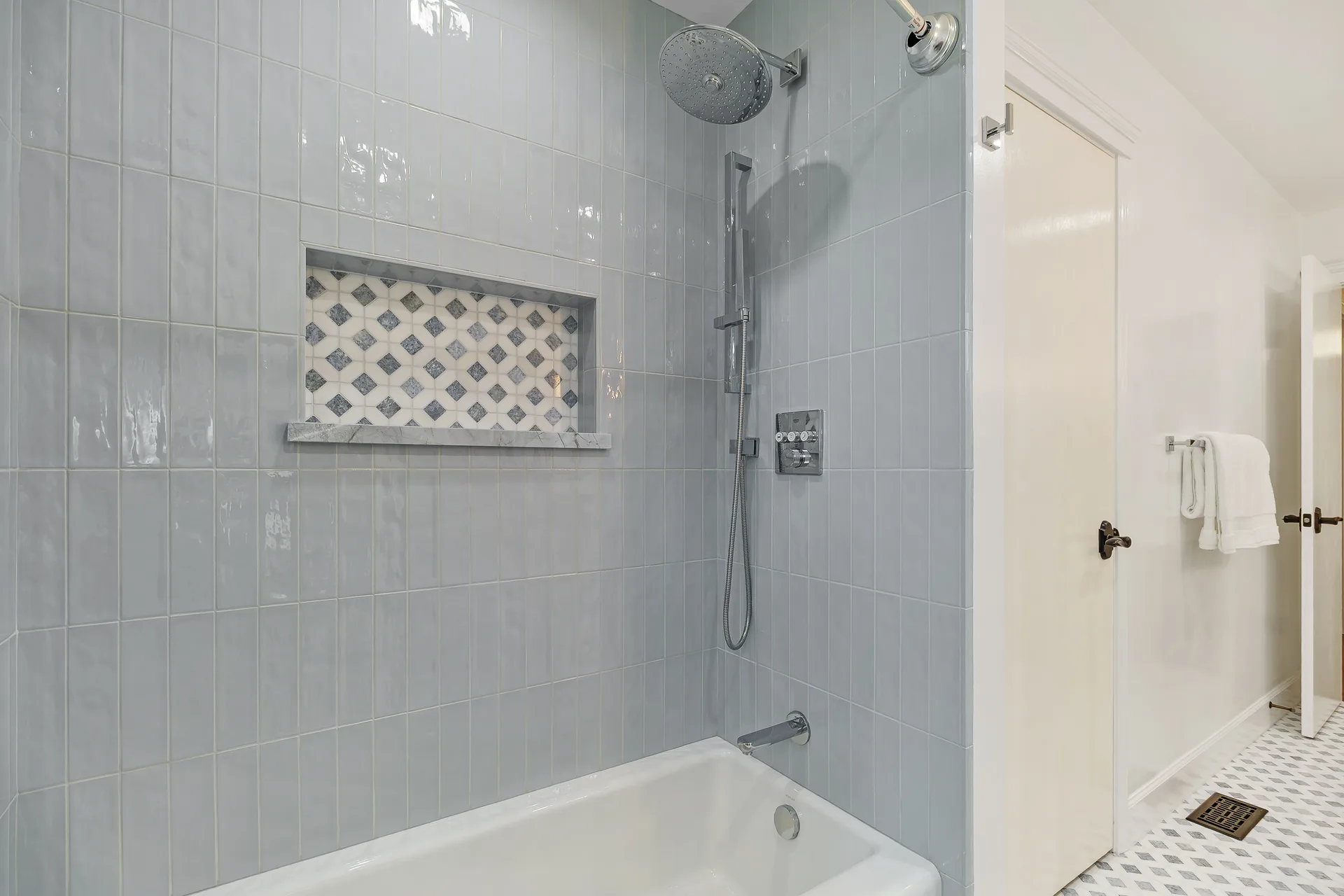 Bathroom with light blue tile, mosaic niche and a deep soaking tub