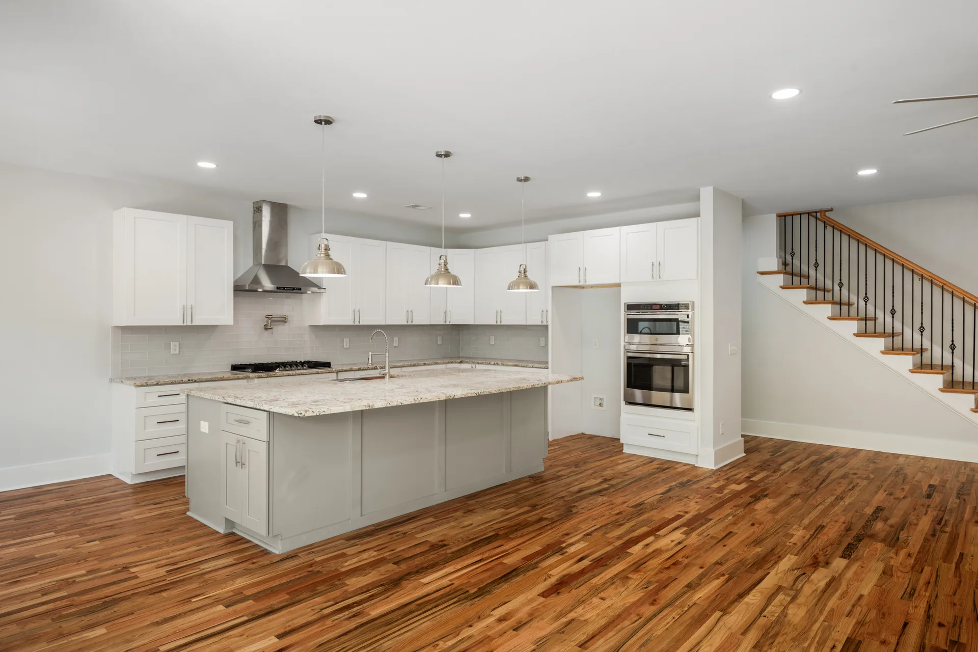 Modern kitchen with white cabinetry, grey island with granite top, and stainless appliances