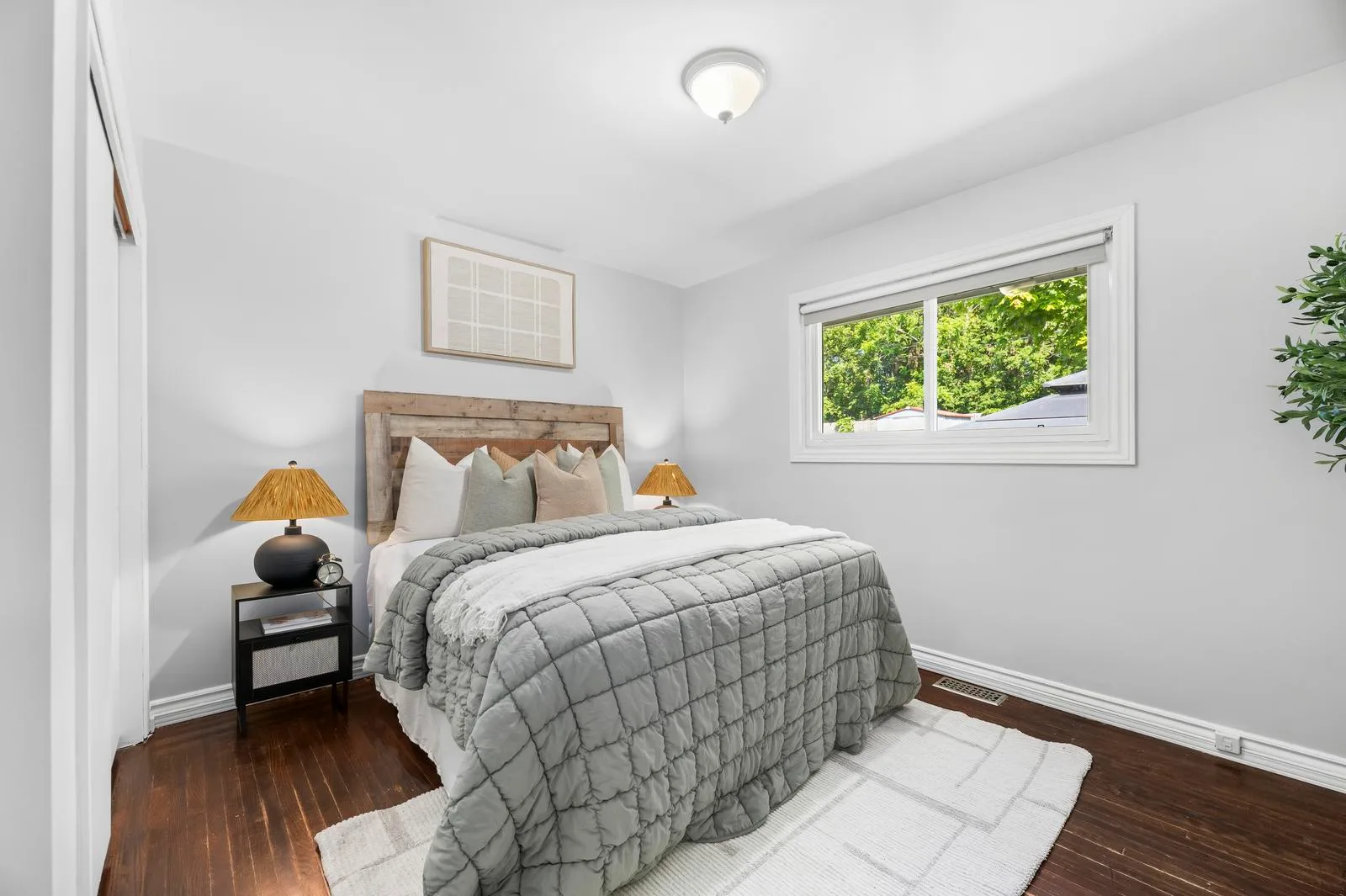 Guest bedroom with hardwood floors and neutral light grey walls