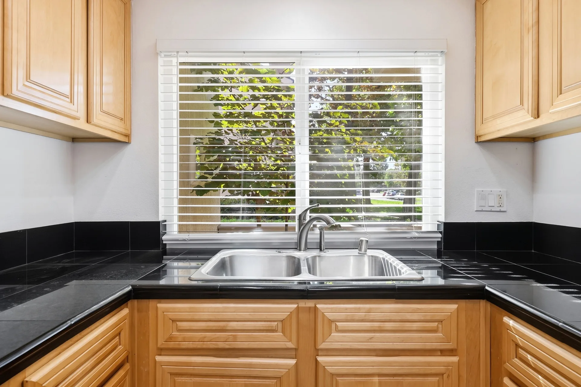 Kitchen sink and window at 8 Silverwood with natural daylight and a view of the greenery outside