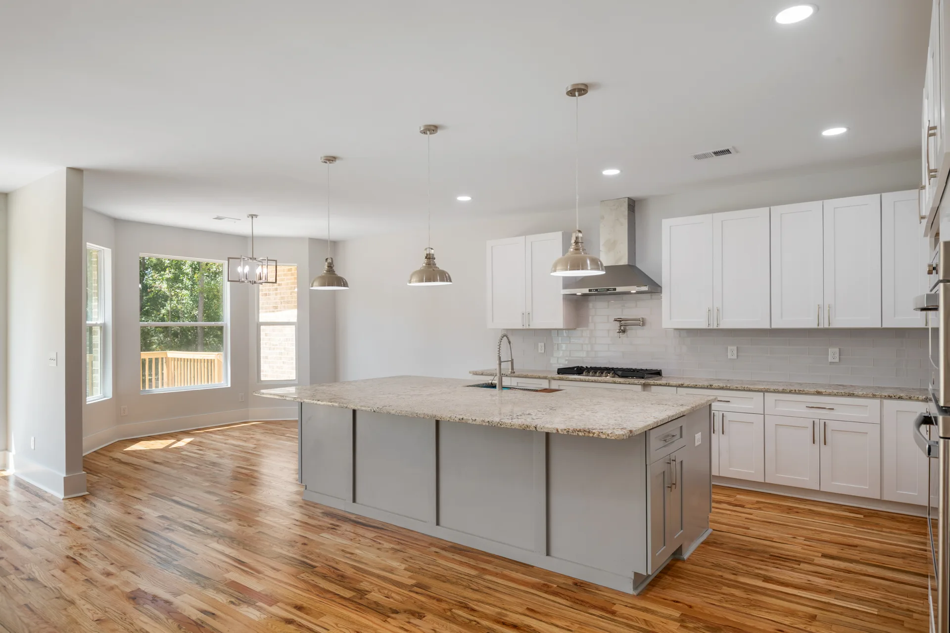 Large grey island, tiled backsplash and pendant lighting