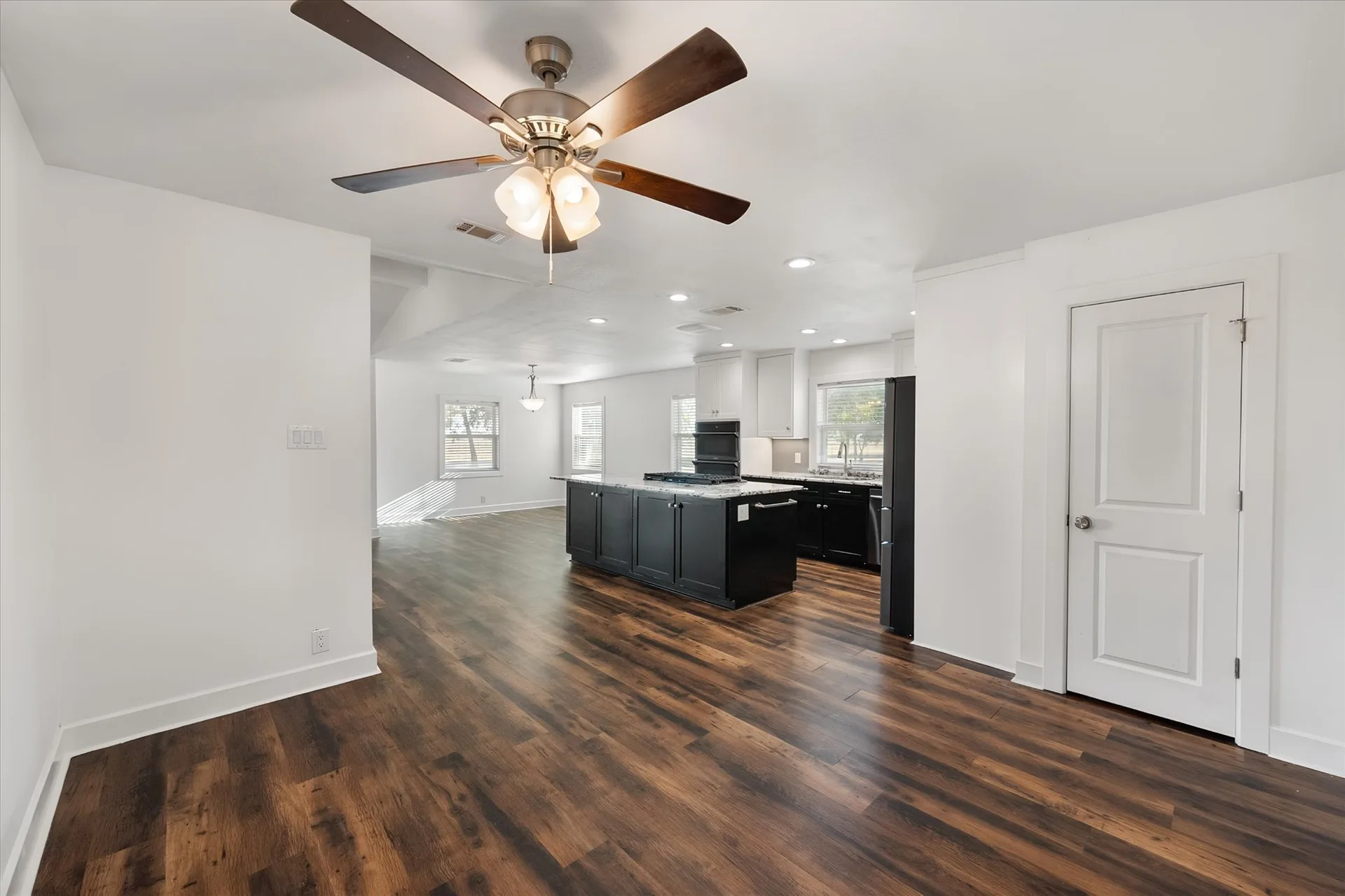 Renovated kitchen and dining area with dark cabinetry and stone counters