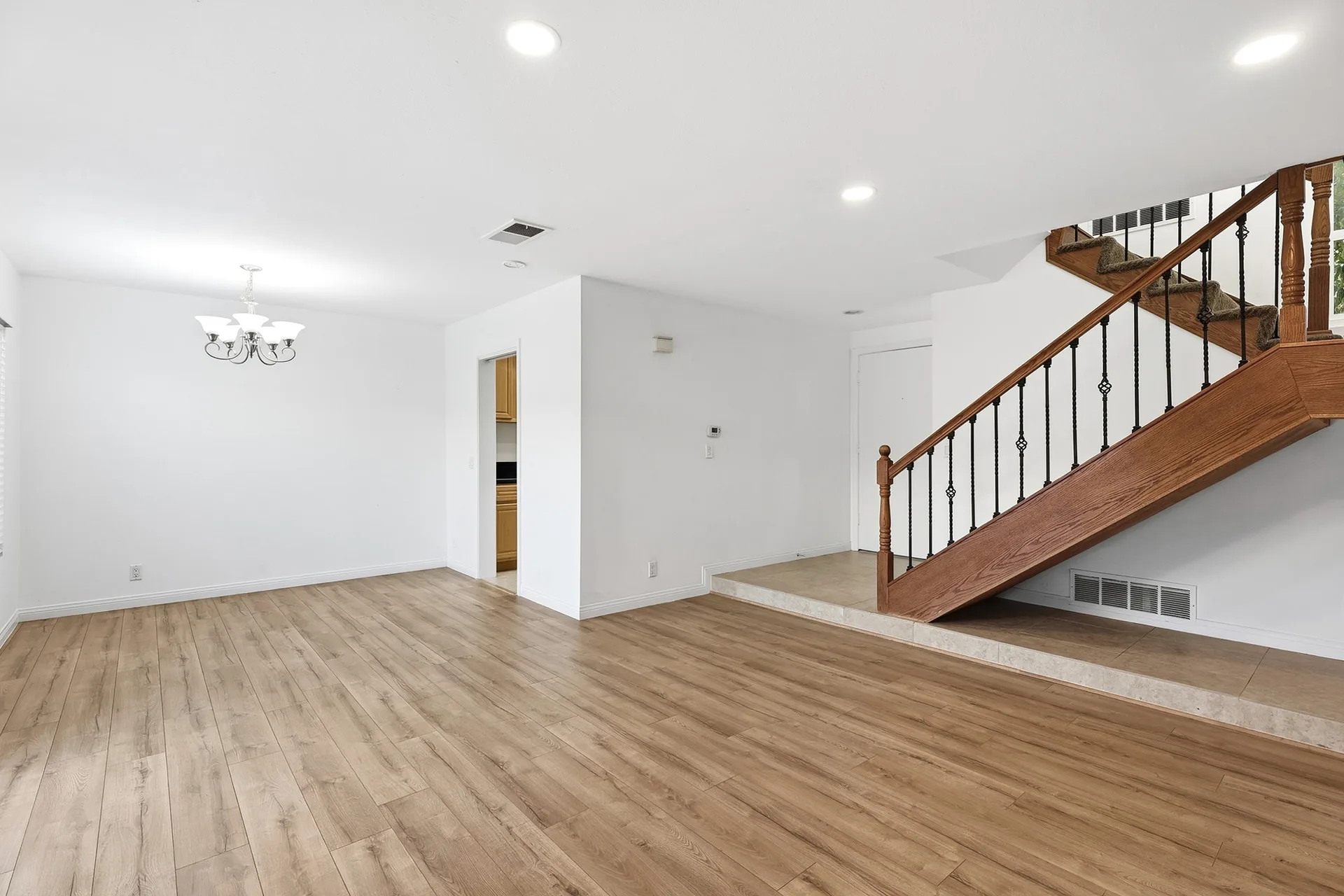 Open-plan living and dining space at 8 Silverwood with a staircase with black metal balusters and a chandelier