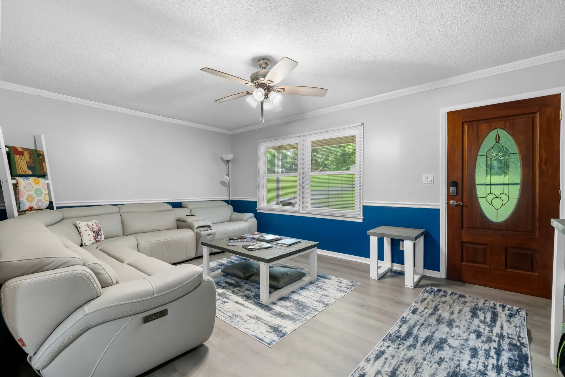 Family room at 4690 Worth Pl looking toward the front entry door, with two-tone blue and white walls and wood-look flooring