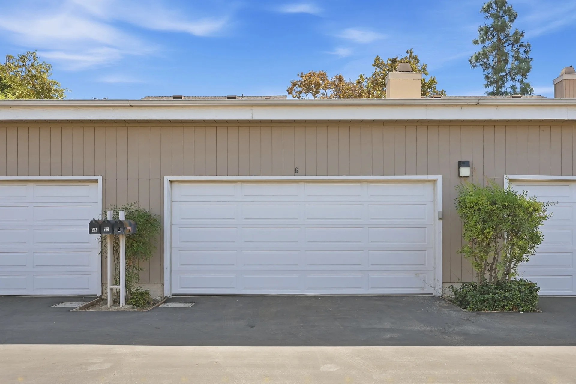 Attached two-car garage at 8 Silverwood with white garage doors and vertical siding