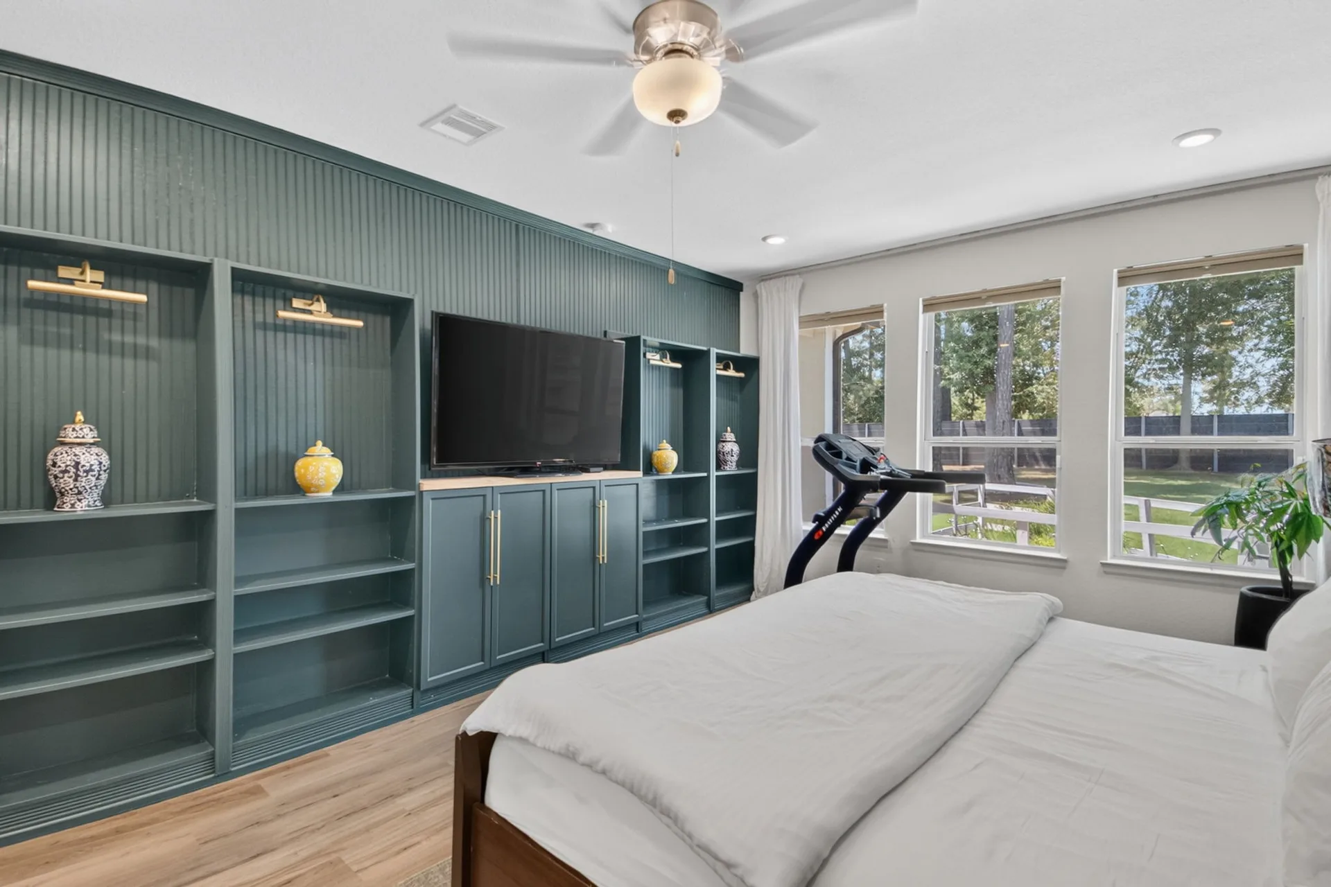 Primary bedroom with floor-to-ceiling custom cabinetry, integrated lighting, and tall windows