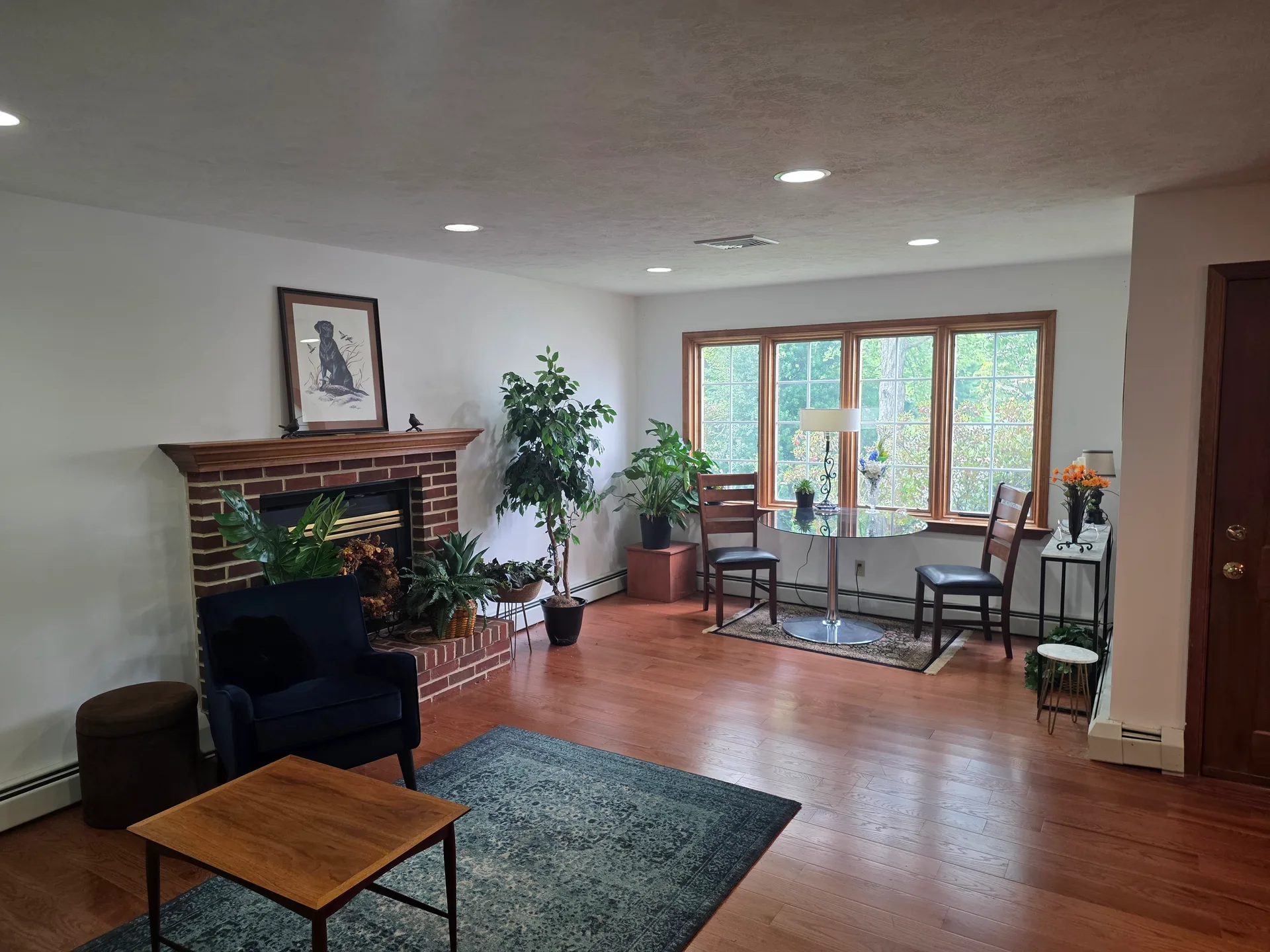 Living room with brick fireplace, recessed lighting, and hardwood floors