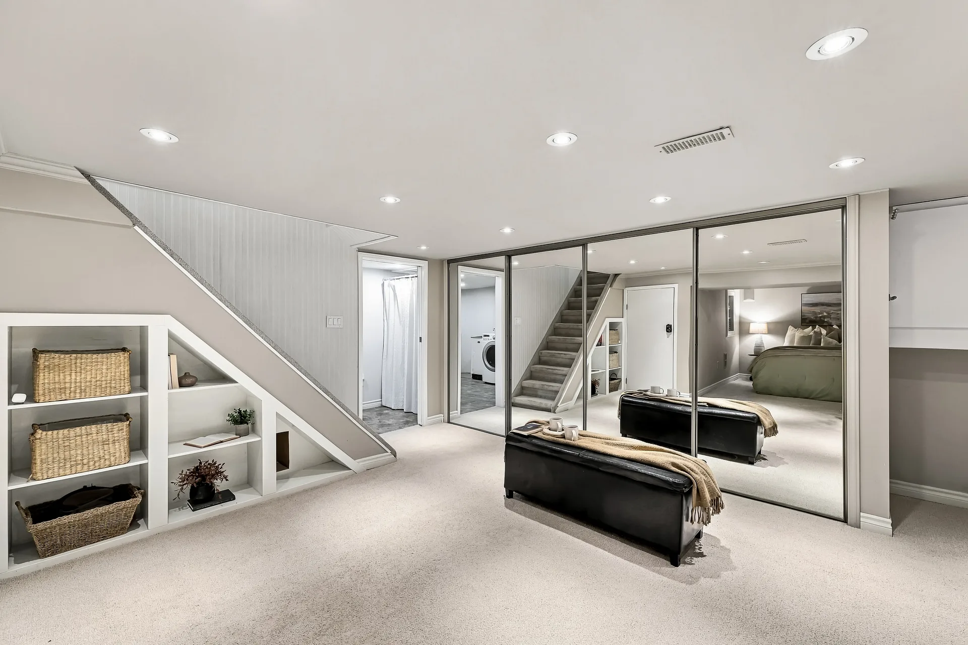 Lower-level bedroom with mirrored closet doors and under-stair storage