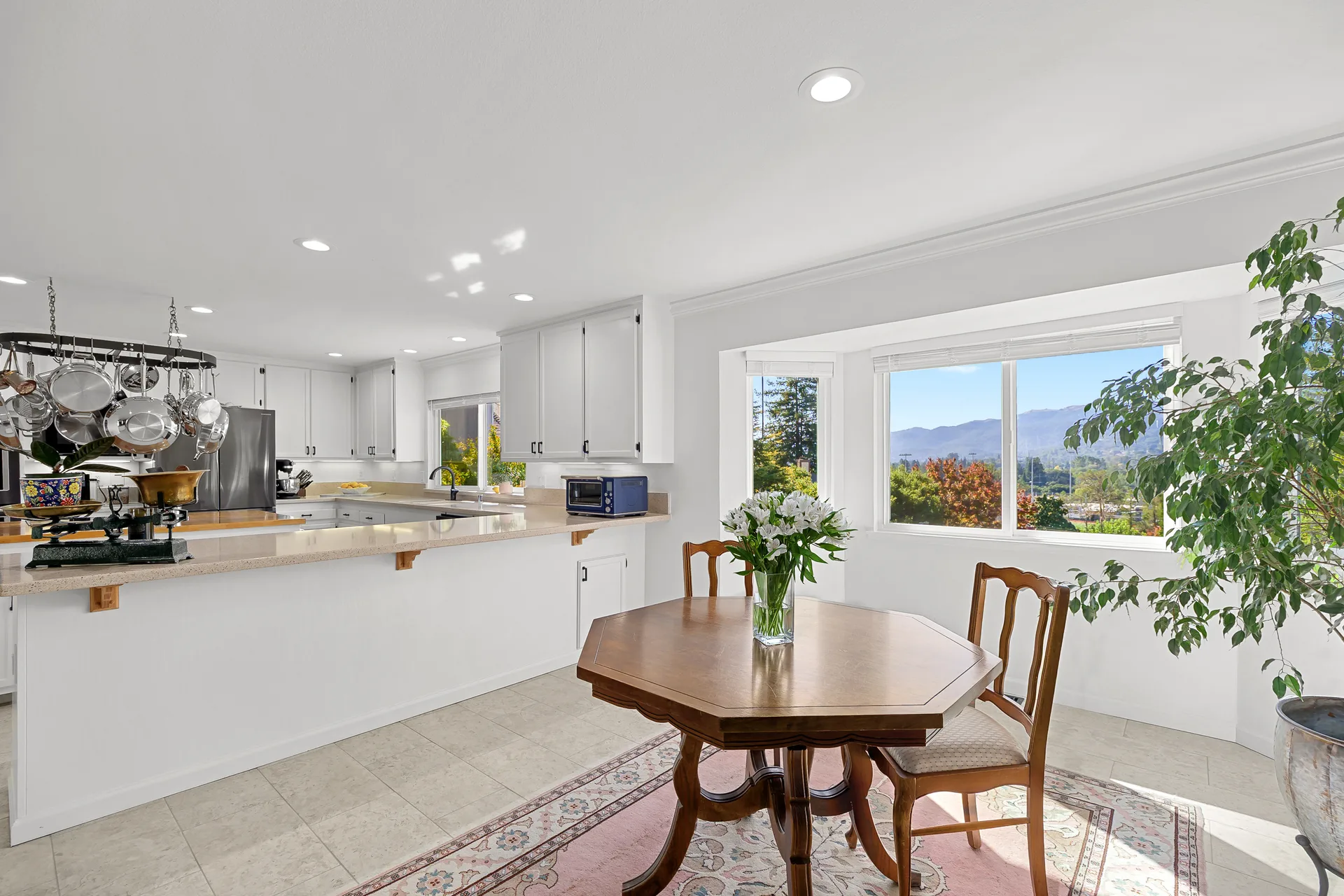 Kitchen flowing into a dining area with hillside views through large windows